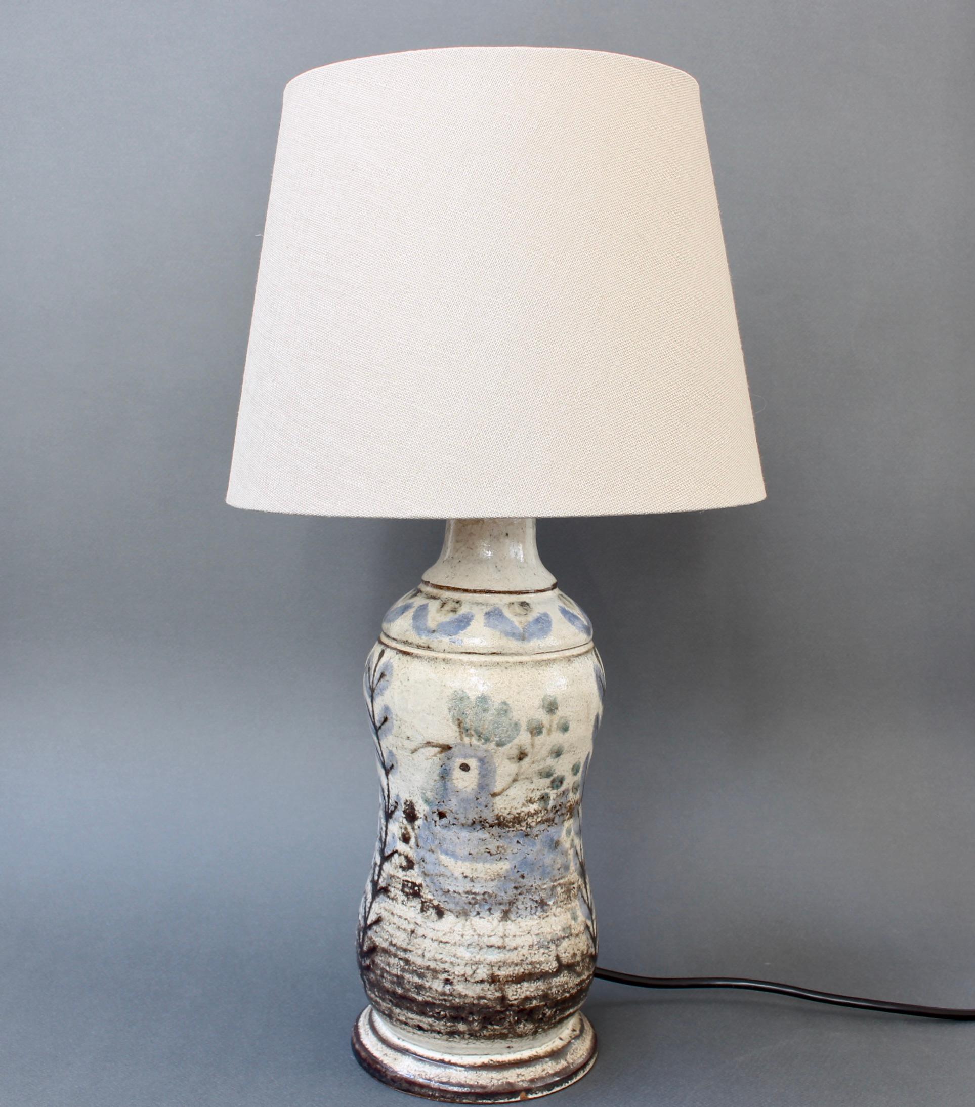 French ceramic table lamp (circa 1960s) by Le Mûrier studios. A charming and very delightful table lamp with French rooster and plants motif decorated on a gourd-shaped body. Blue painted accents cover the milky-white ceramic with darkened, earthy