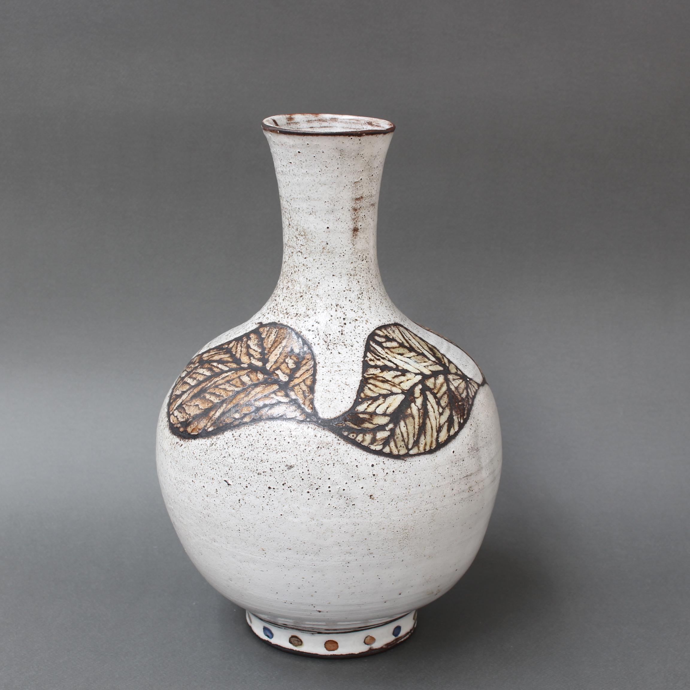 Vintage French ceramic vase by Paul Quéré (circa 1970s). A chalky-white base is accentuated with a stunning leaf motif, mosaic-like in its decoration. An elegant rounded body narrows to form a long, graceful neck. At the base is a smaller, round