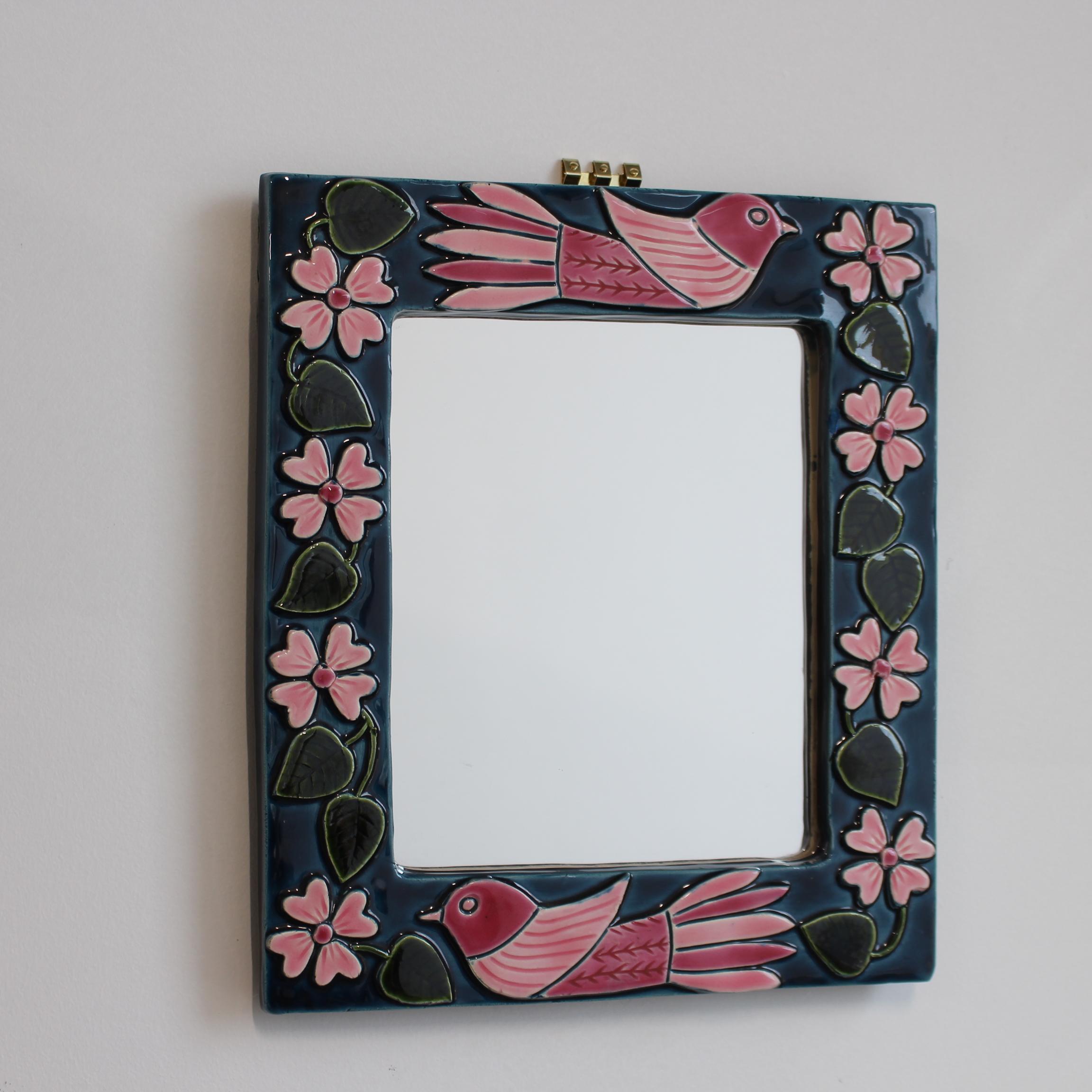 Miroir mural en céramique du milieu du siècle avec émail, motif floral et oiseaux stylisés par Mithé Espelt (vers les années 1960). Un miroir mural décoré de façon fantaisiste avec deux tons de rose dans les fleurs et les oiseaux, le tout sur fond