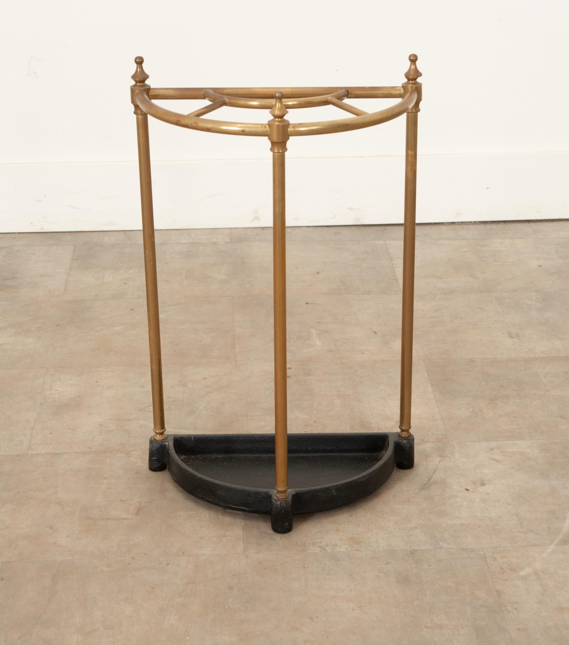 A classic vintage French demi lune brass umbrella or walking stick stand. Elegant and well made, this brass hallway, entry way or closet umbrella or cane stand has five compartments, three decorative finials, and a cast iron drip tray. Constructed