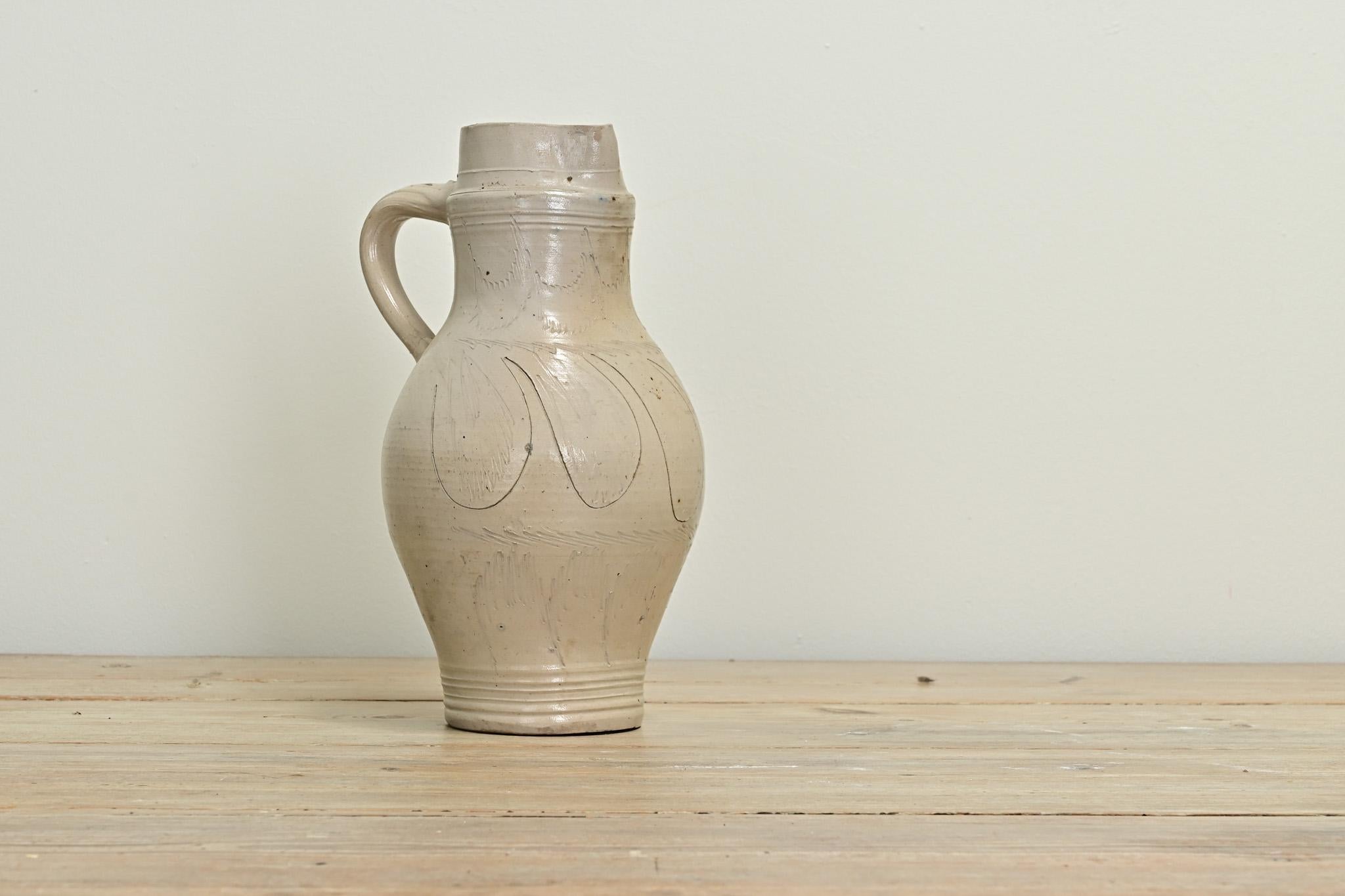 This French earthenware jar adds character to any interior with its unique texture, etched pattern, color, and patina. The jar has a handle and spout perfect for using or for decoration. Be sure to view the detailed images to see the current