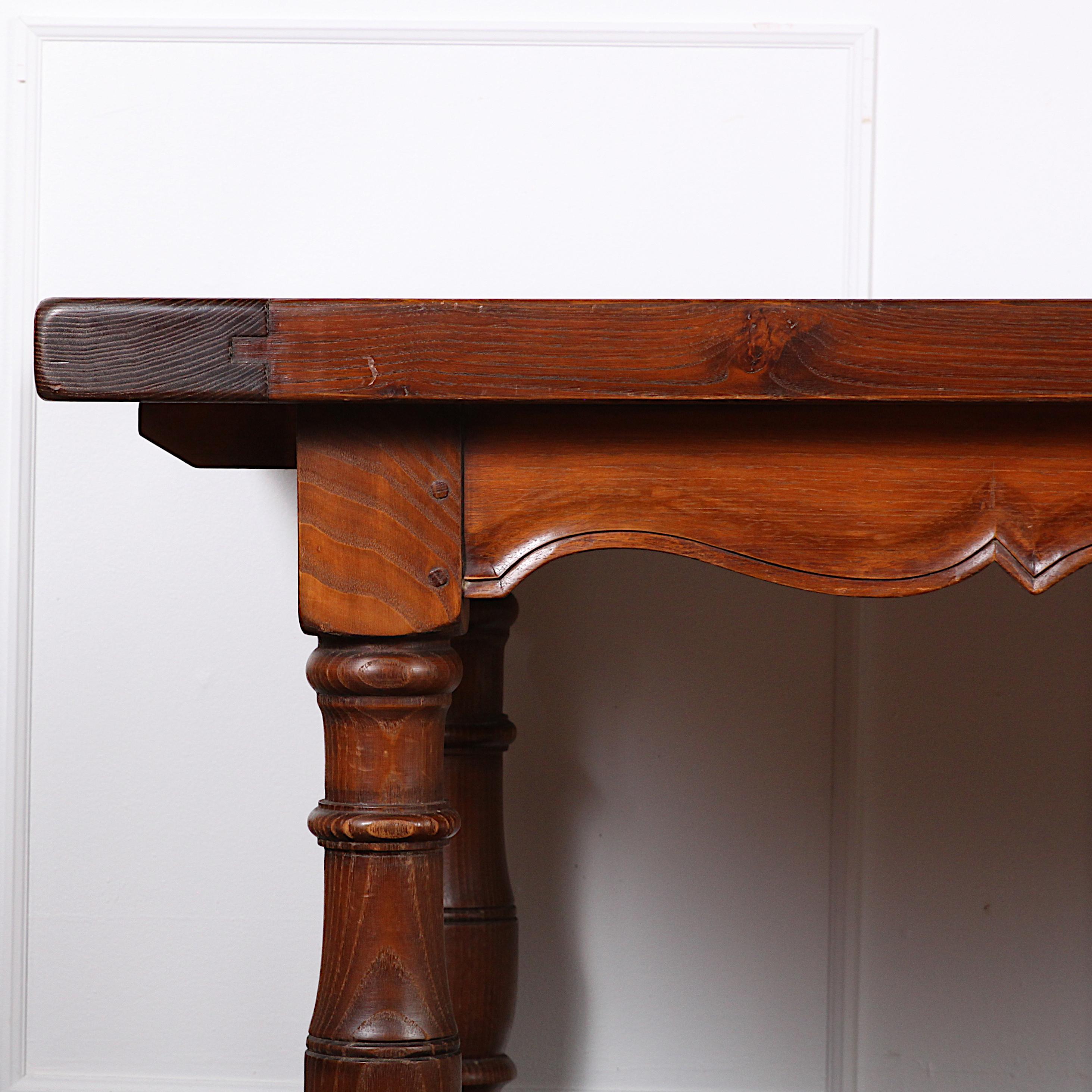 French vintage farm or trestle table in solid elm planks, the top with scalloped carved skirt, the whole raised on turned legs with a trestle 'H' stretcher.