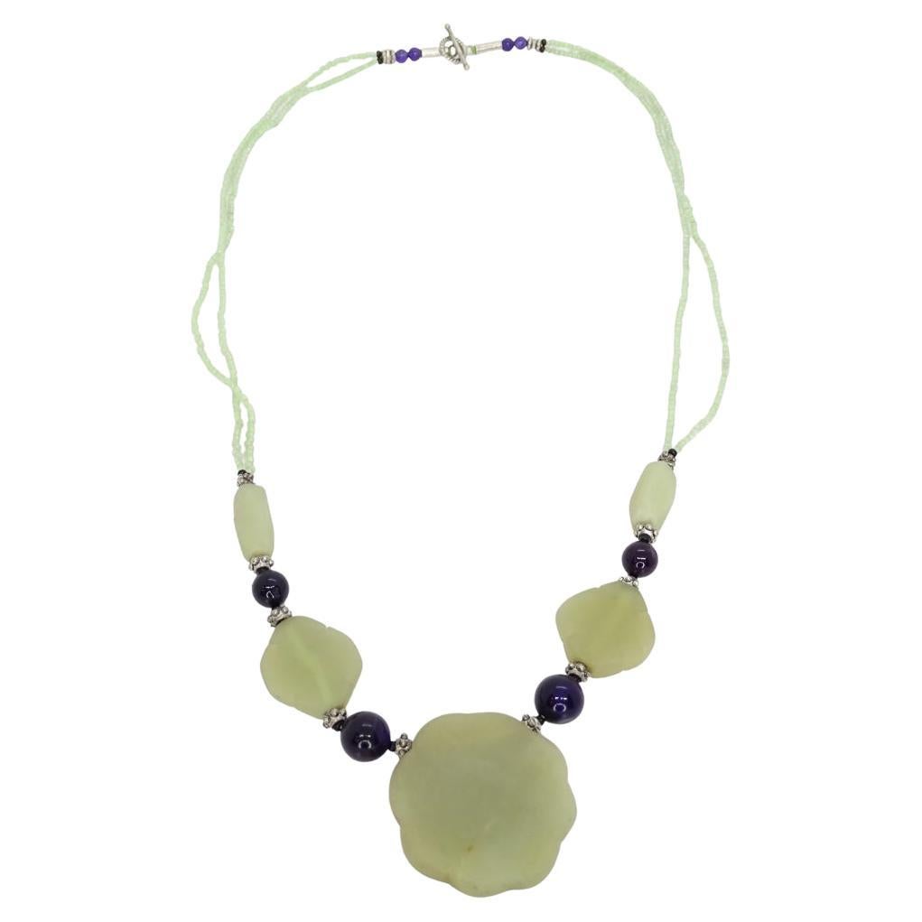 
Delicate and gorgeous Asian-inspired necklace with flat jade flowers and dark blue glass beads.

This necklace is composed of a double strand of translucent green glass beads. The design features a sequence of polished jade stones in various