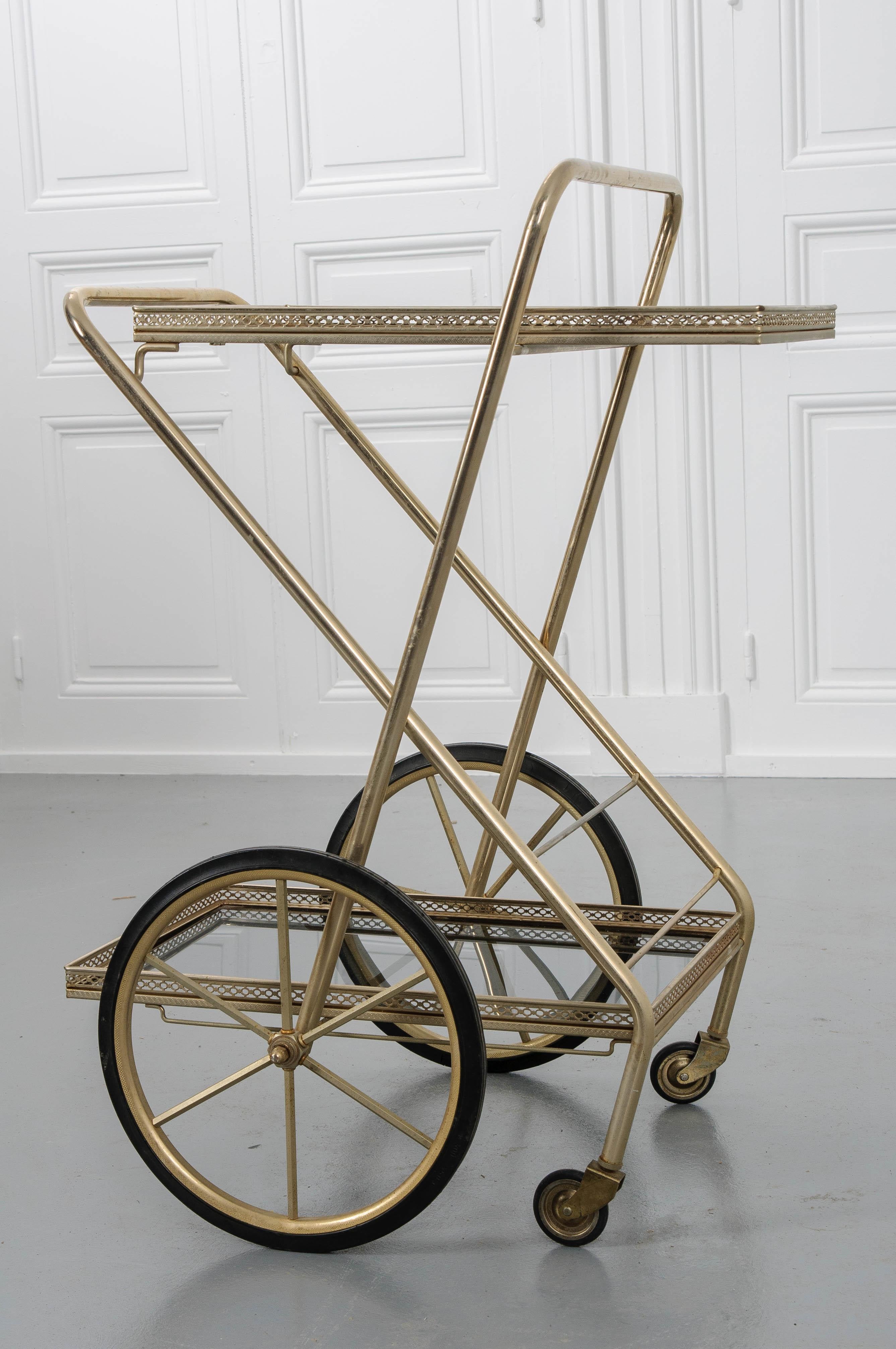 At first glance, this French neoclassical-styled brass plated bar cart looks like many of the other beautiful antique trolleys and service carts that grace many of today’s well-appointed homes. What makes this vintage cart special is its ability to