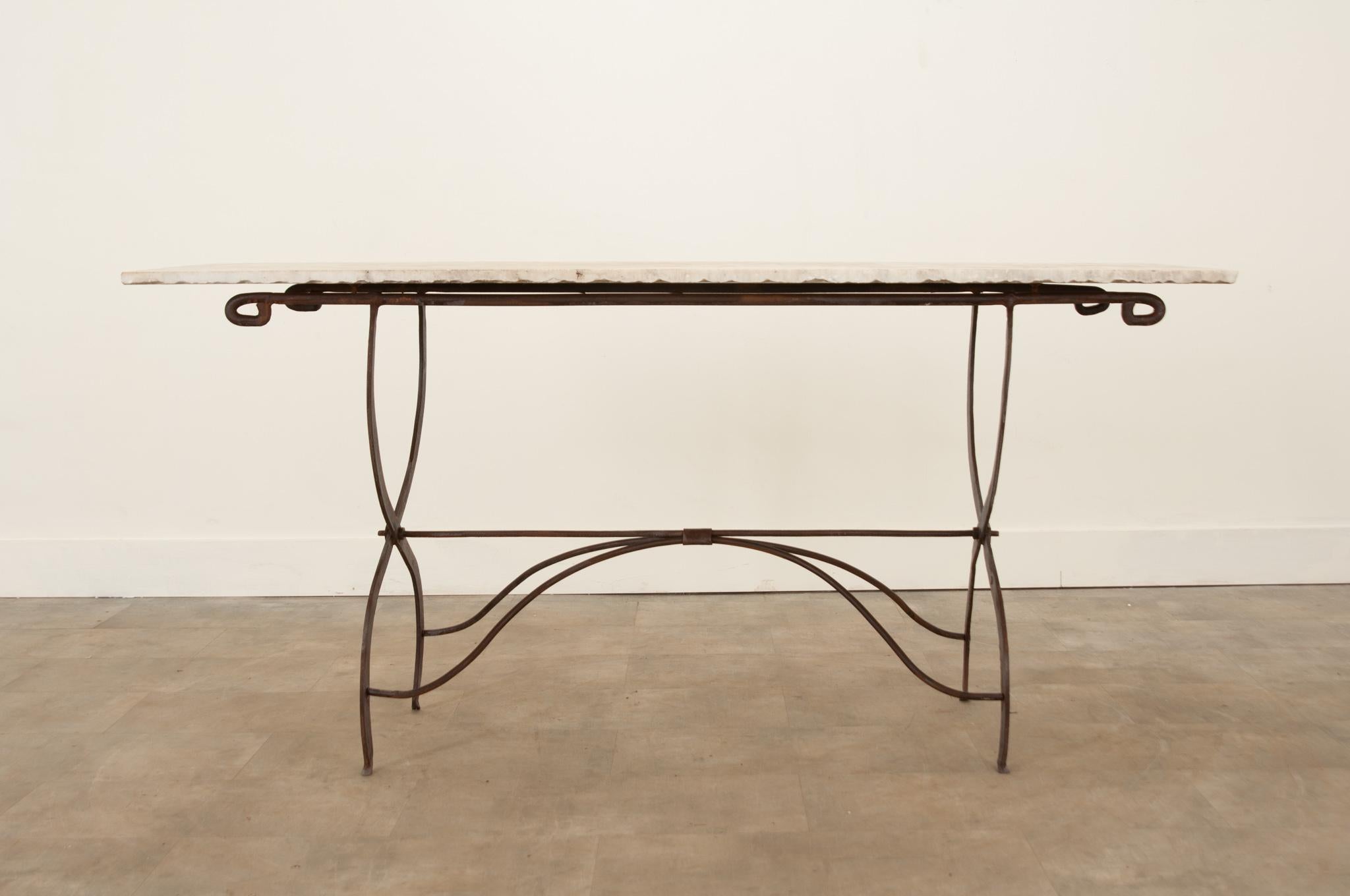 A fantastic bistro table from France, circa 1920s. Its uniquely shaped forged iron base has gained a wonderful patina and is topped with a long piece of white marble with characteristic raw edges. The width between the legs is 39-?”. Make sure to