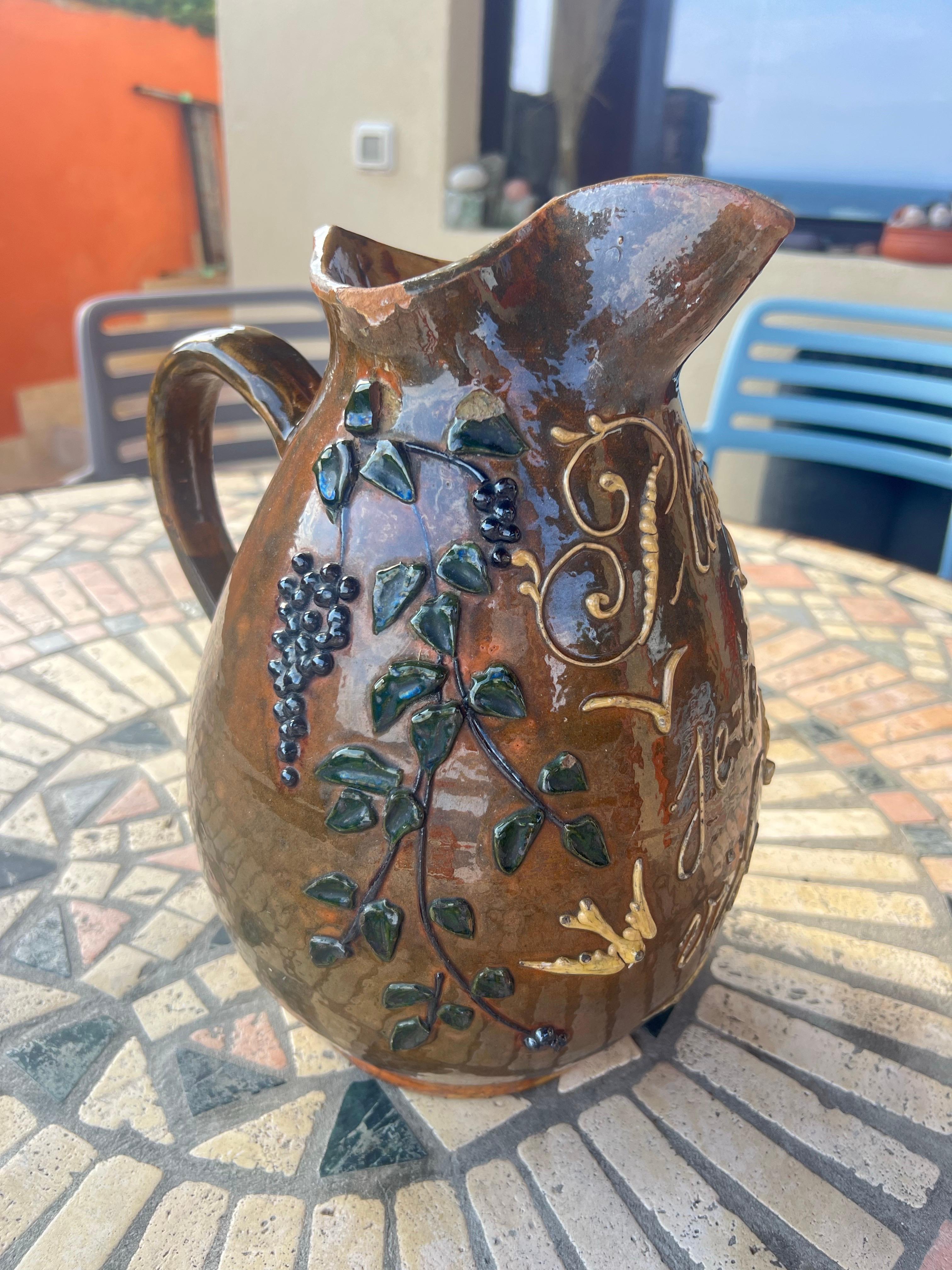 Vintage Handcrafted Ceramic Pitcher – Embossed Grapevine Motif
Condition: Vintage – Fair (chip on spout)

This charming vintage ceramic pitcher features a warm brown glaze with beautiful hand-embossed grapevine and leaf motifs, accented with green
