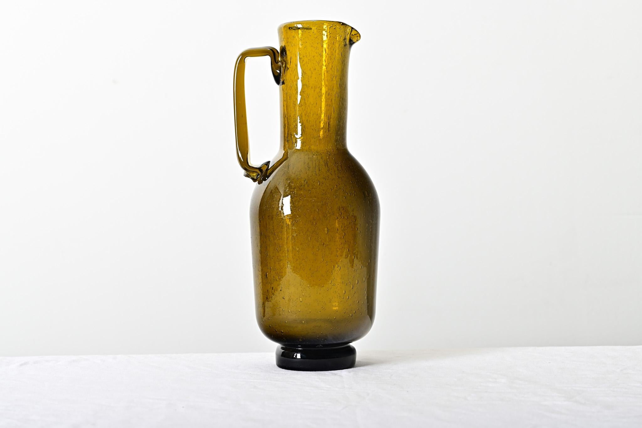 Un pichet français vintage en verre ambré épais avec l'effet 