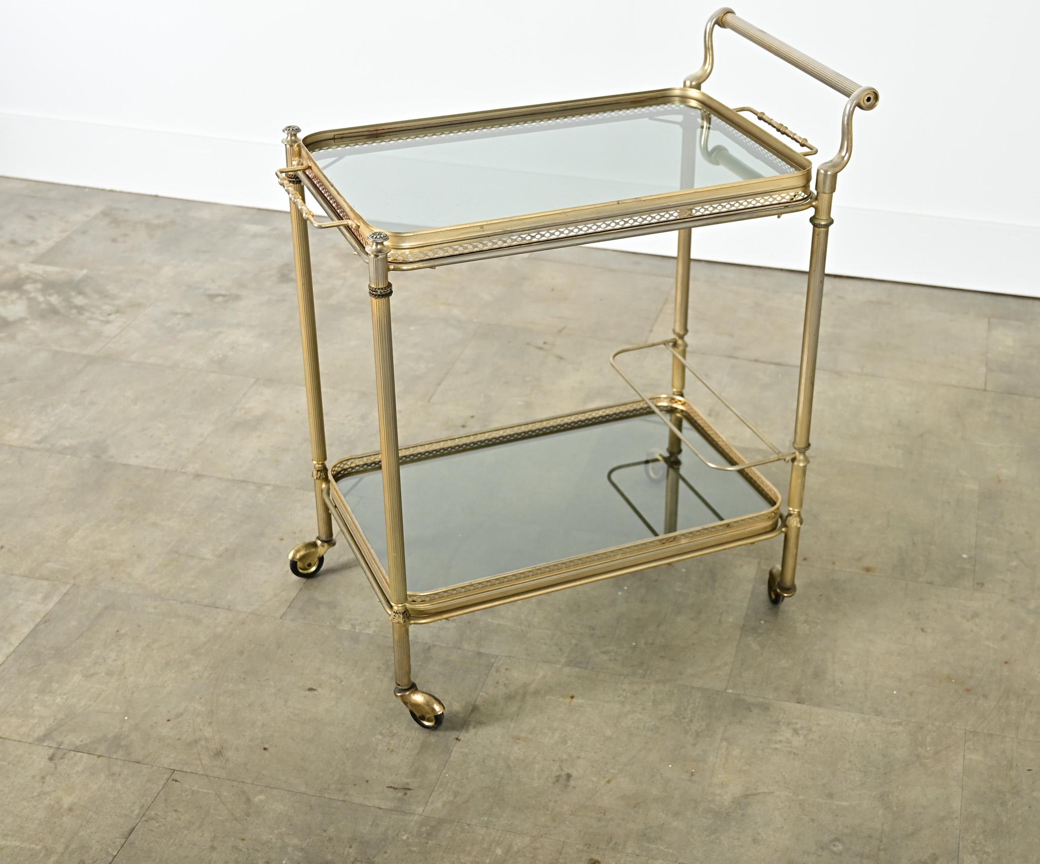 Un élégant chariot de bar français en laiton et verre fumé du milieu du siècle, dans le style de la Maison Jansen, qui serait à l'aise dans une gamme de goûts de décoration allant de Hollywood Regency à plus traditionnel. La structure en laiton