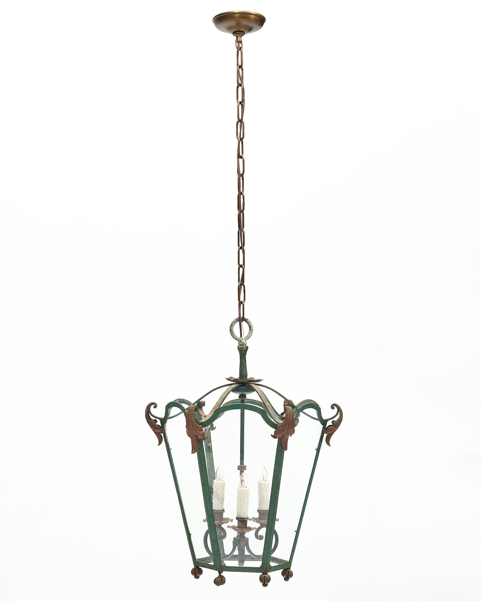 Lanterne de la période Art déco en France. Ce luminaire est fabriqué en fer forgé avec six panneaux de verre entourant trois lampes intérieures à base de candélabre. Un décor de feuilles d'acanthe orne cette pièce de couleur verte. Il a été