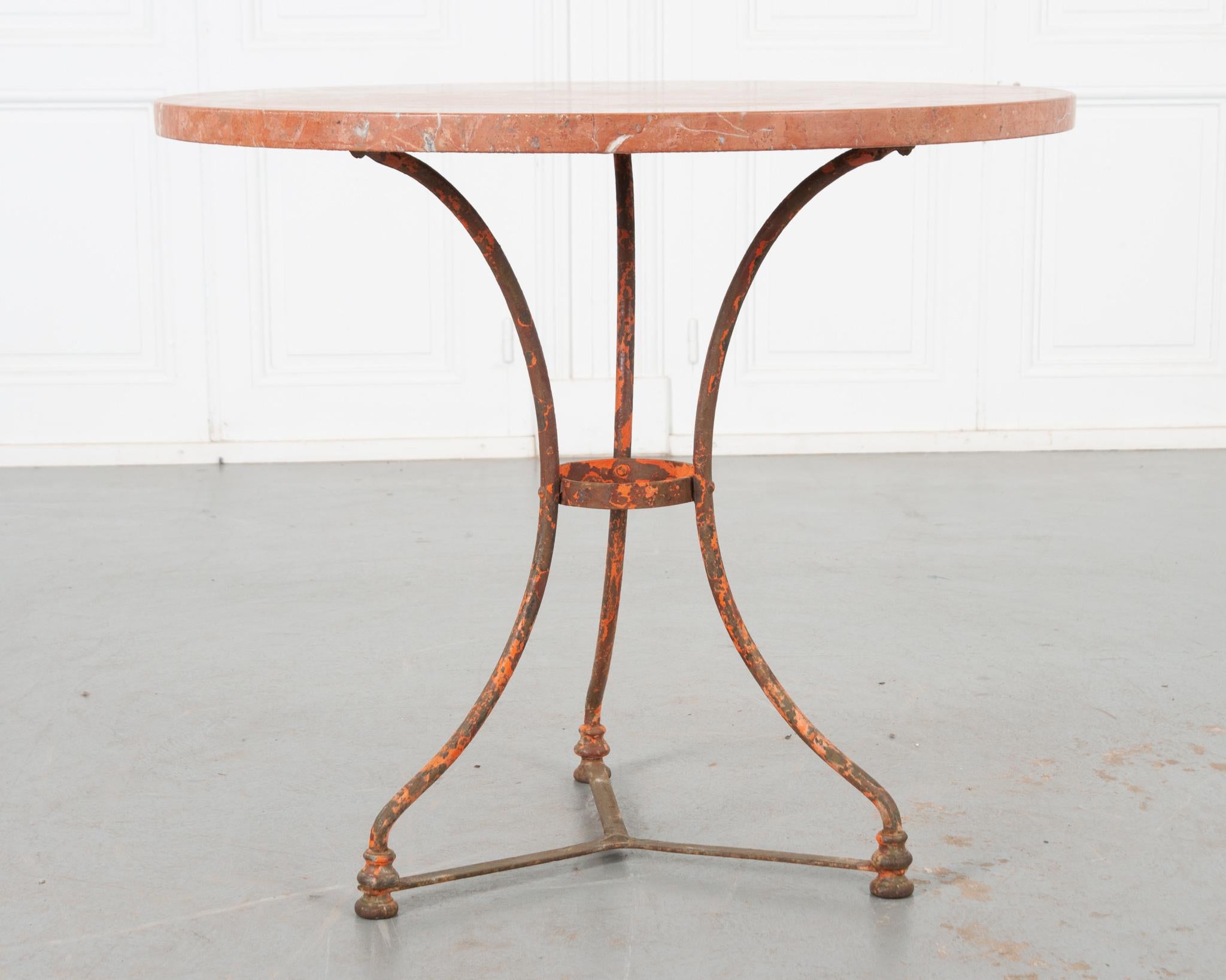 This darling vintage bistro table is the perfect way to add a pop of color and texture to any space! The red marble top is in great condition and beautifully compliments the worn orange and red painted iron base. Three legs join at a center ring and