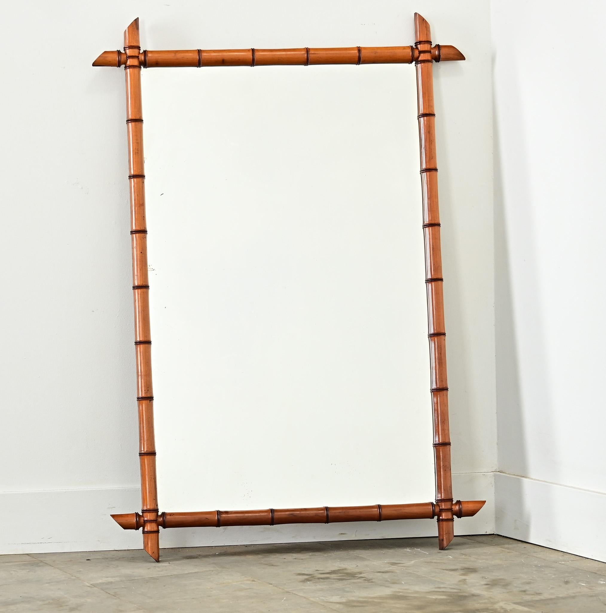Miroir en faux bambou de France, début du 20e siècle, avec une belle patine brun miel dans le cadre. Ce grand miroir présente une silhouette rectangulaire (symétrique pour être suspendu dans les deux sens) en pin sculpté, faux bambou, en saillie