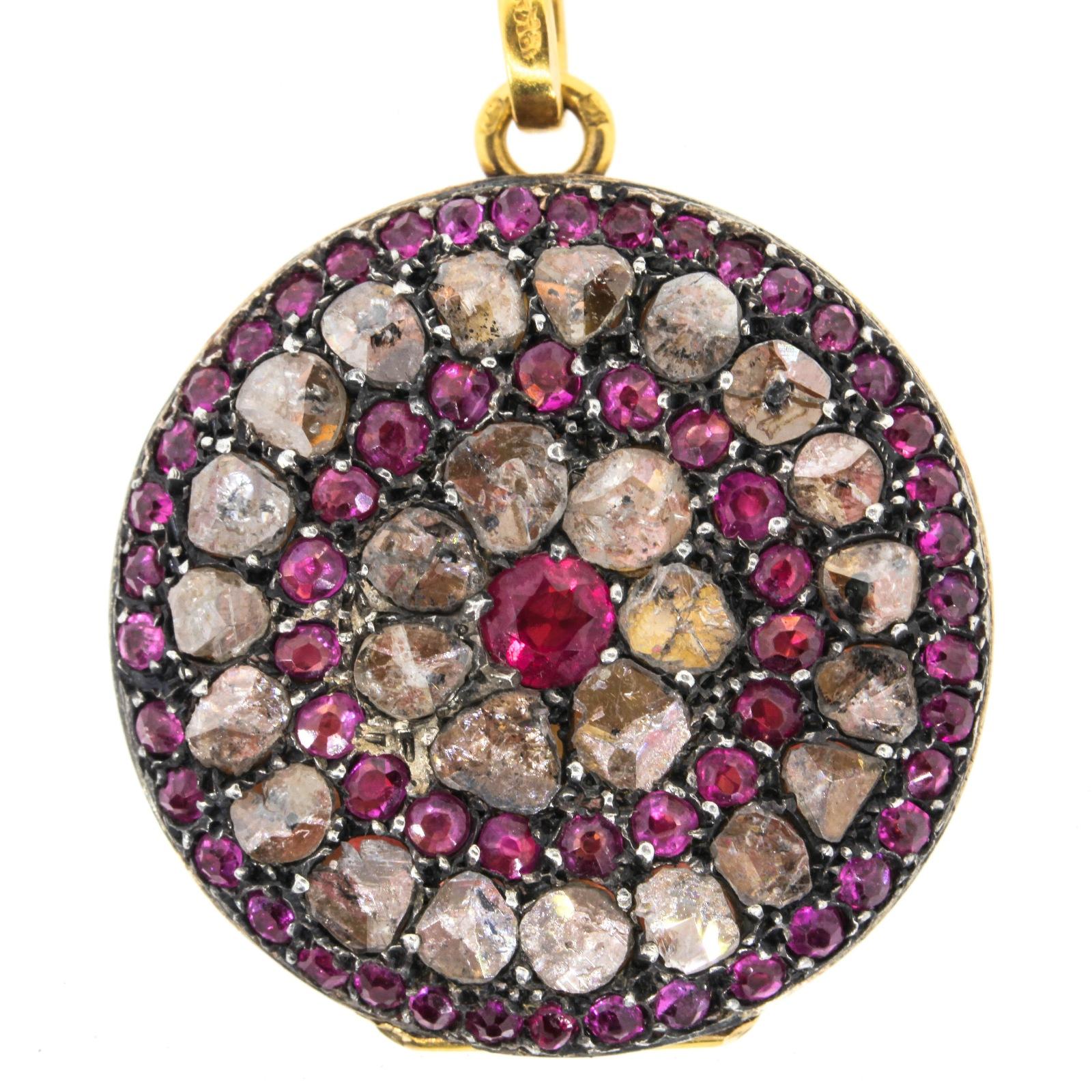 A gorgeous French circa 1900s 18KT yellow gold locket, adorned with sixty Burma Rubies weighing approximately 2.30 carats and 4.40 carats of rough and beautiful Rose Cut Diamonds.  The locket measures  1 1/4 inch in diameter, and the loop is marked