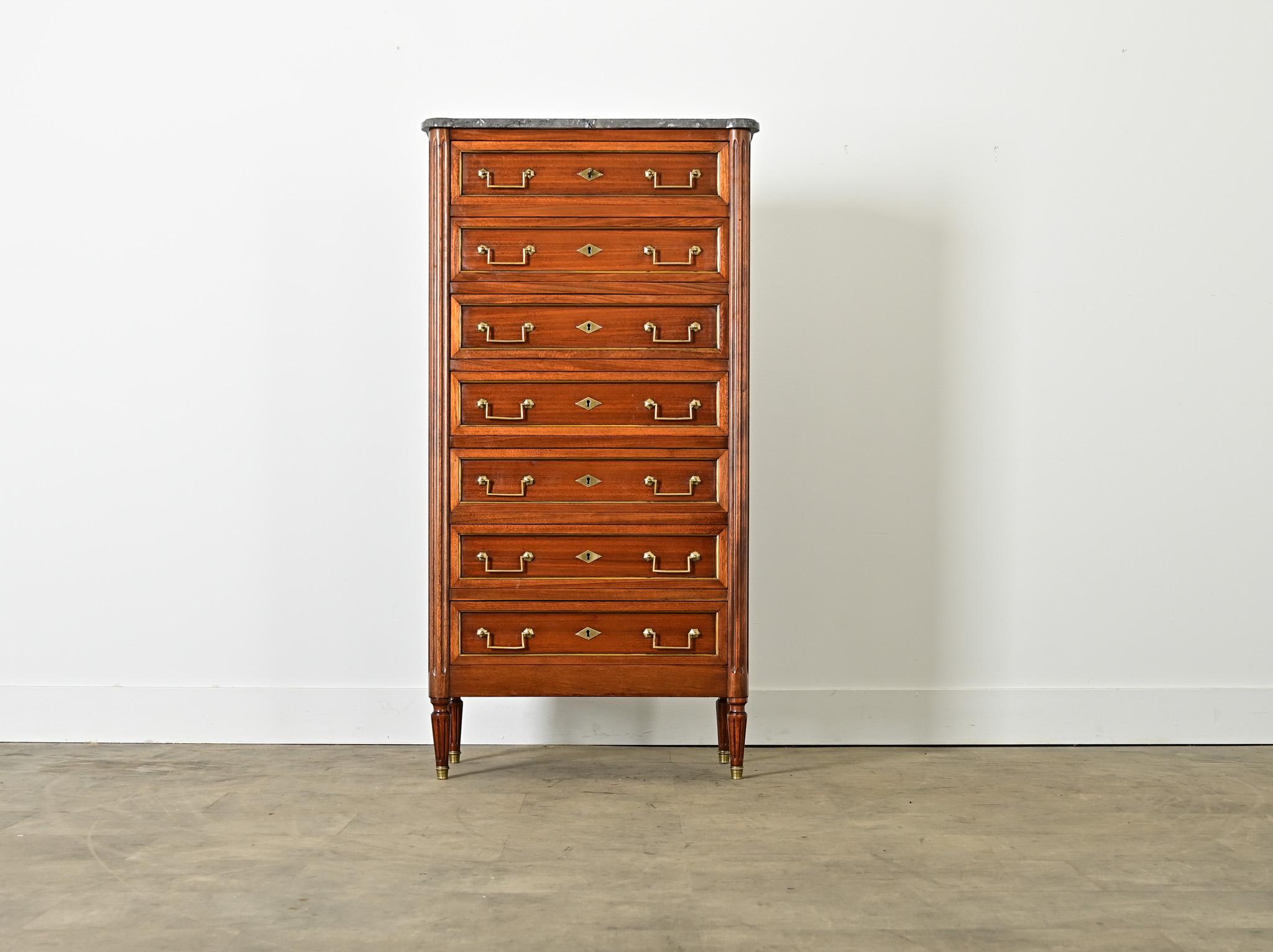 French mahogany vintage 20th century semainier–crafted in the Louis XVI style and quality–this Neoclassical dresser offers seven drawers (one for each day of the week) outlined in brass and crowned with a marble top. The top surface of smoky gray