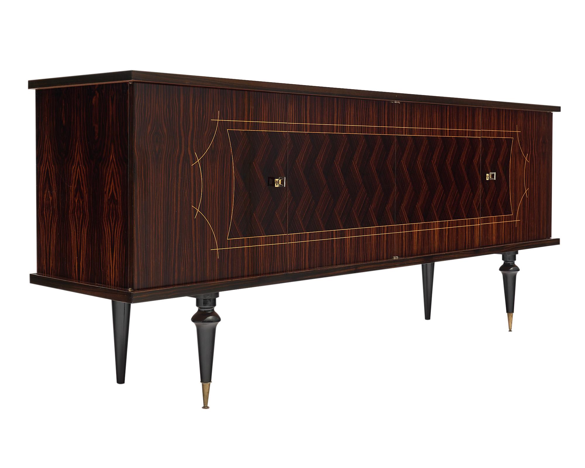 Buffet, French modernist, made of Macassar of ebony wood in a chevron decorative pattern and satin wood inlays. This enfilade features four ebonized turned legs supporting a cabinet with two sets of double doors closing on adjustable lemon wood