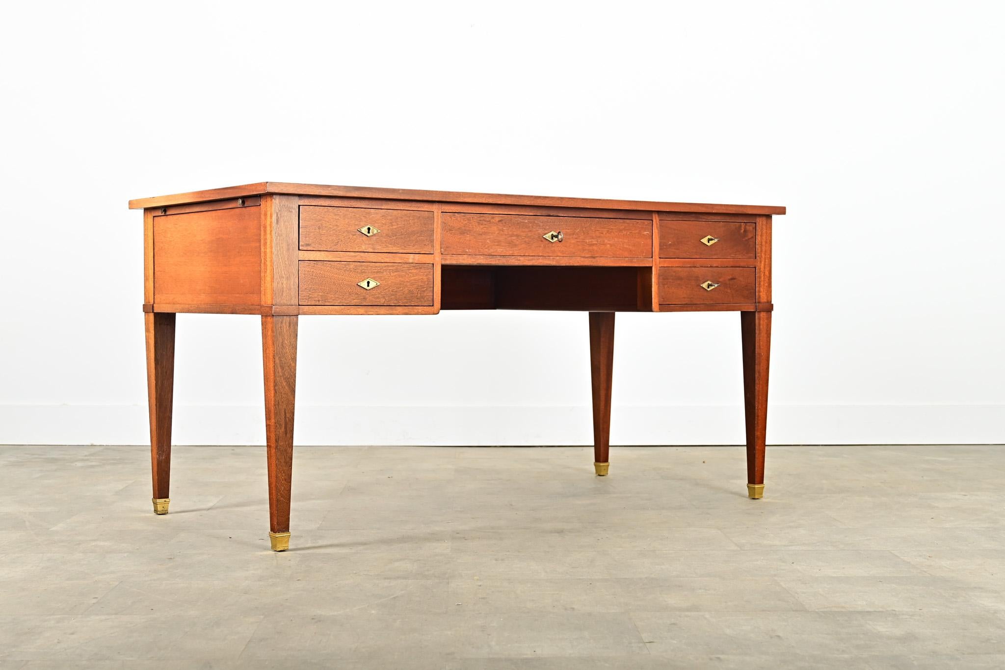 A French vintage leather-topped mahogany writing desk, designed in the Directoire taste for refined proportions & materials. Two hidden extensions on each side add occasional surface area. The wide, cognac leather surface is worn and outlined in