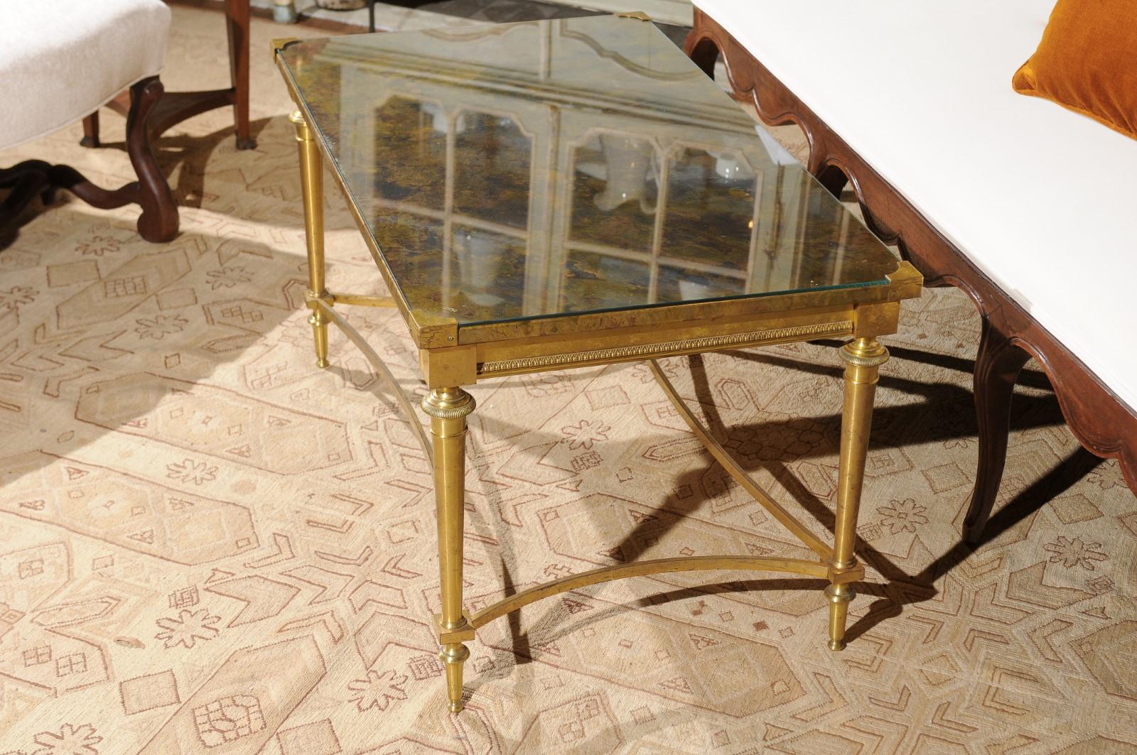 A French Maison Baguès brass coffee table from the mid-20th century, with glass and marbleized top. Born in France during the midcentury period, this Maison Baguès coffee table features an exquisite rectangular marbleized top protected under custom