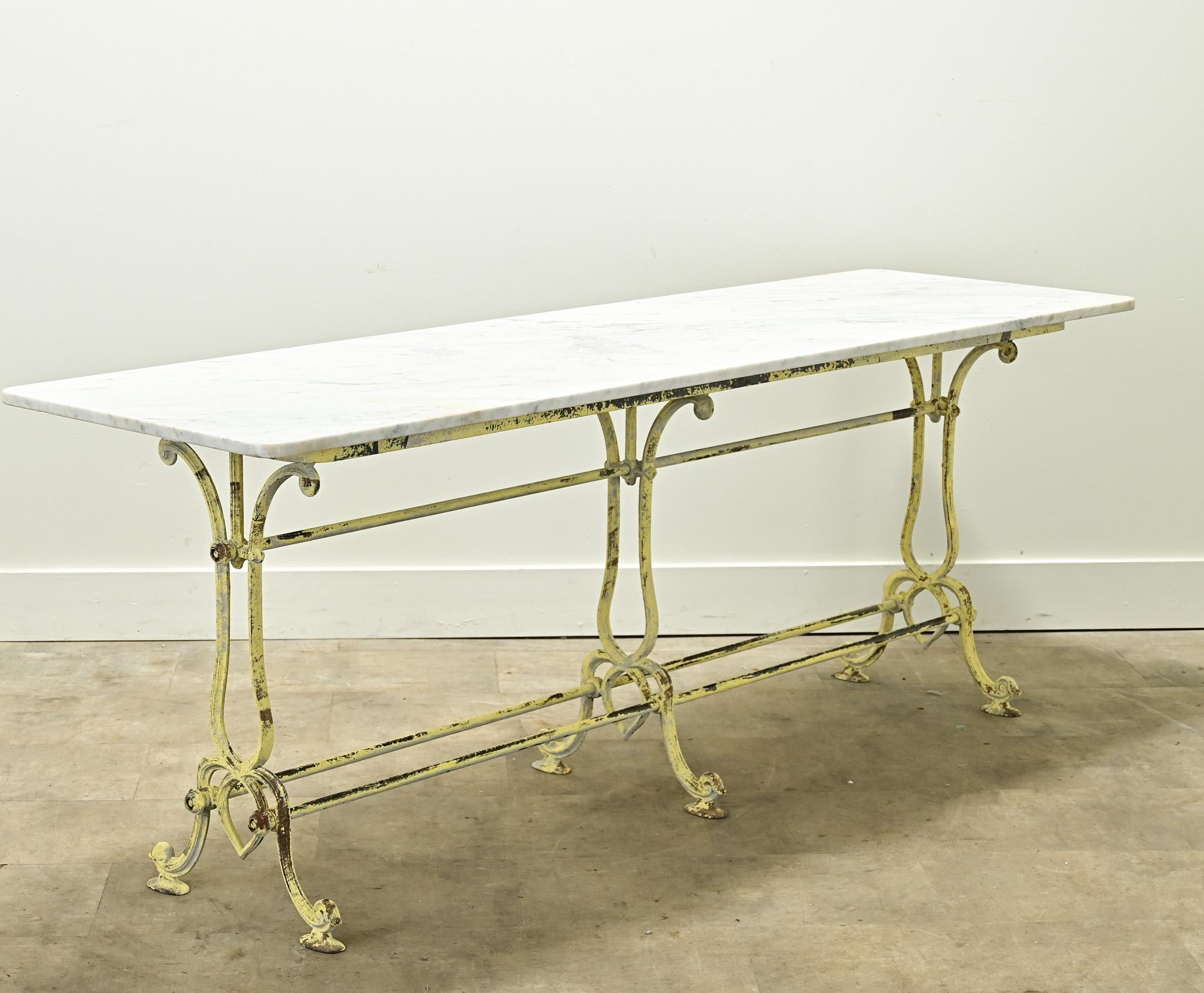 A long vintage bistro table with a white marble top and worn painted base. This table has a durable surface and could be used as a long console or for dining. Be sure to view the detailed images to see its current condition. 