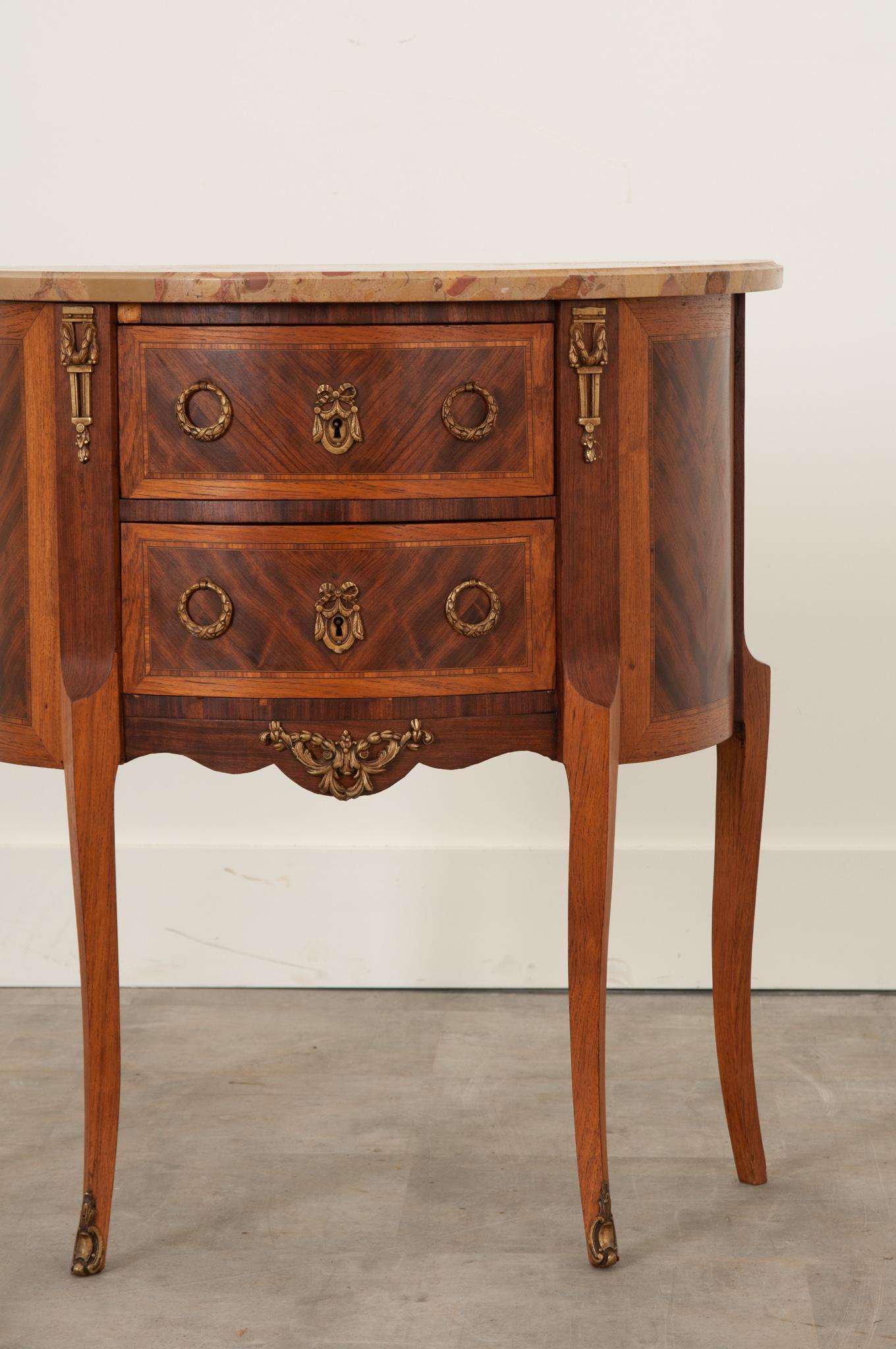 This striking little demilune chest features exceptional inlaid mahogany in varying varieties that have been thoughtfully book matched and placed about the chest to maximize the beauty expressed through its grain. Made in France in 1965, this