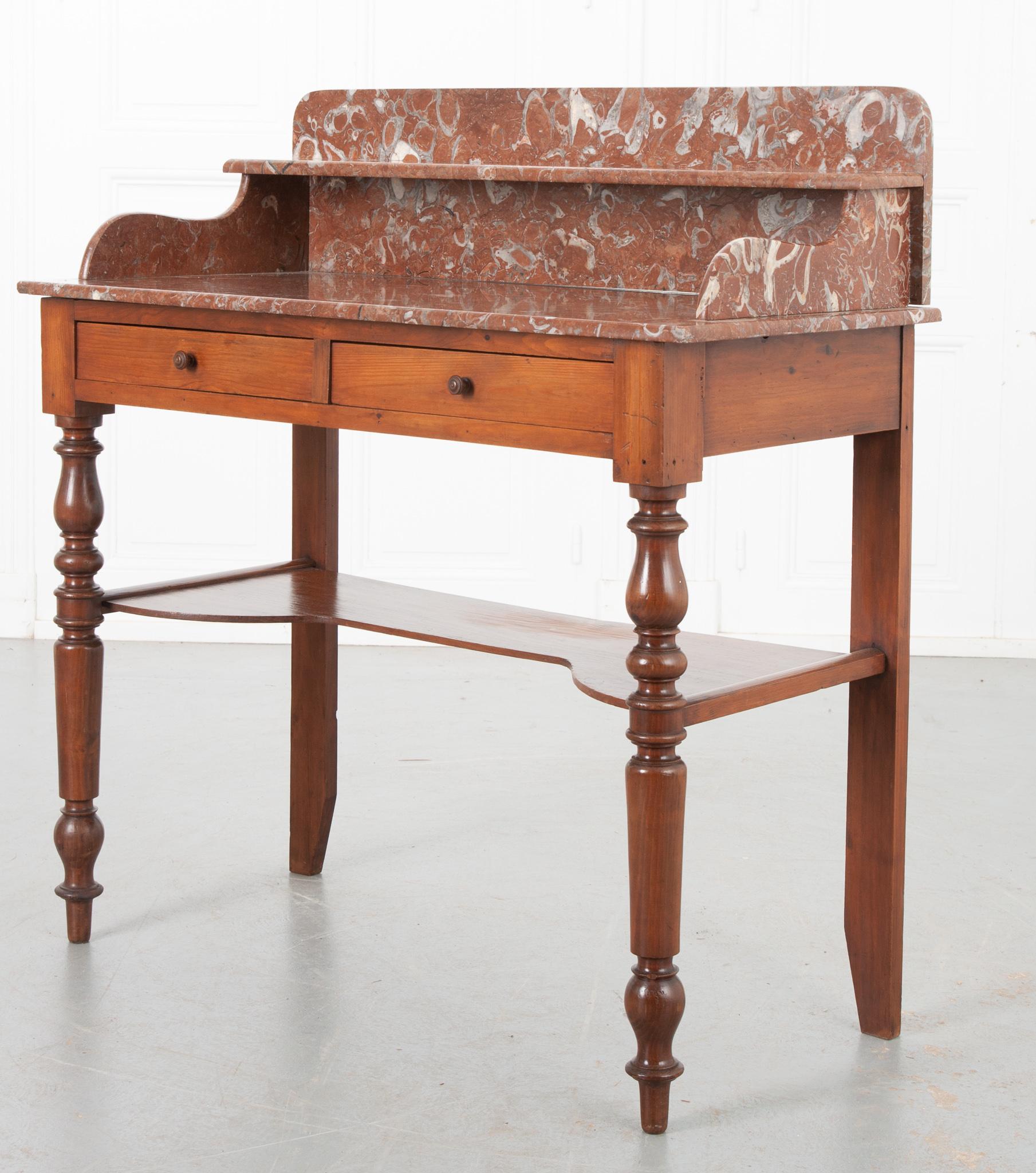 Il s'agit d'une vanité vintage en marbre de France, vers 1920. Il serait idéal placé sous un grand miroir ou avec l'ajout d'un miroir de table. Le plateau en marbre multicolore veiné, majoritairement de couleur rouille, comprend une petite étagère
