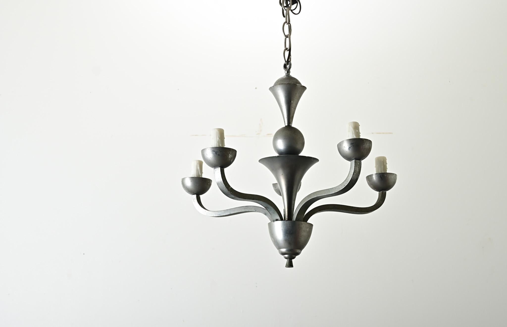 Un lampadario francese moderno di metà secolo dal fascino senza tempo. Forgiati in metallo con un tenue colore peltro, i cinque bracci si protendono con grazia verso l'alto e verso l'esterno dai coni impilati della colonna di sostegno. Pulita e