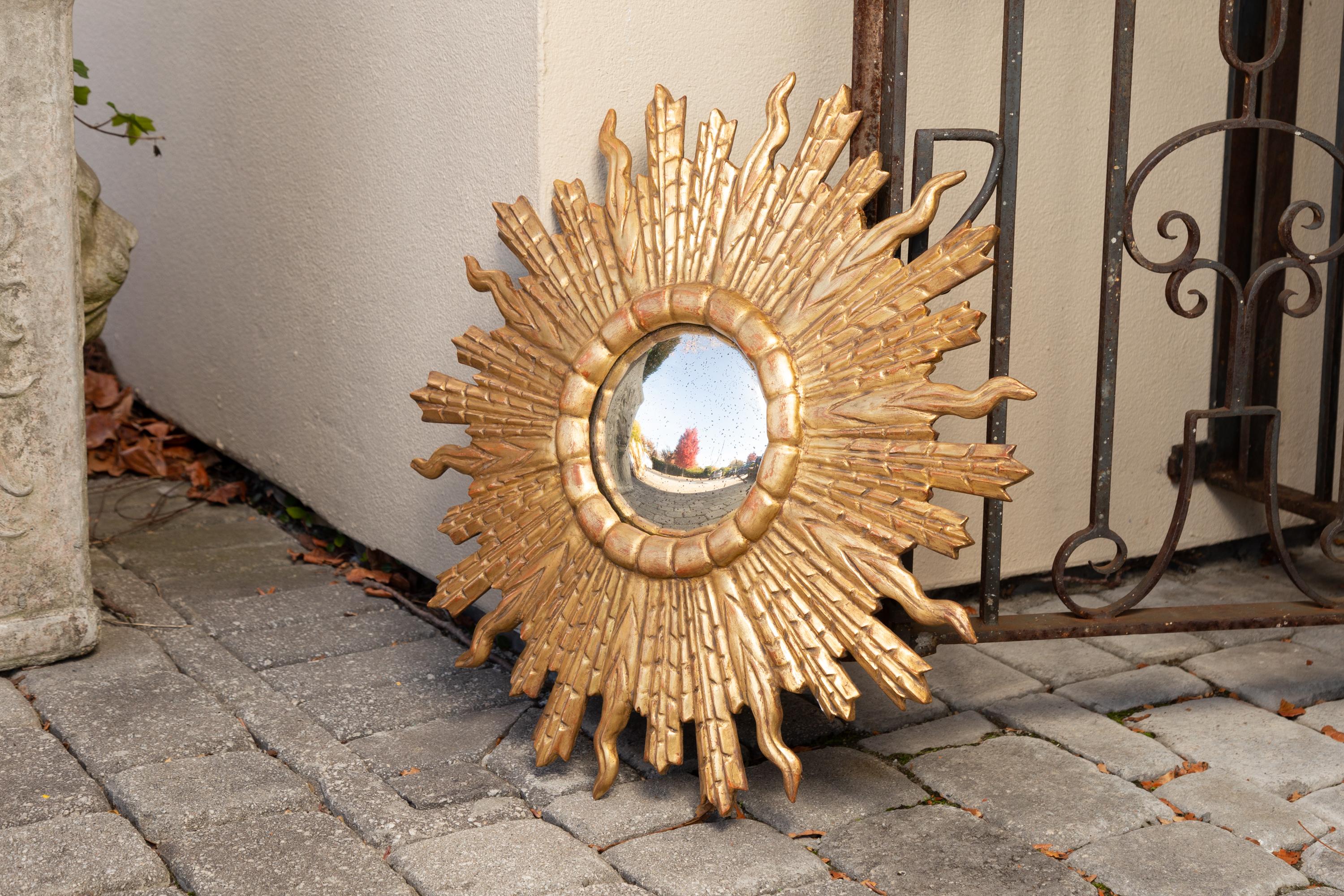 A French vintage giltwood convex sunburst mirror from the mid-20th century, with alternating rays. Born in France during the midcentury period, this exquisite sunburst mirror features a convex mirror plate, surrounded by a circular molding from