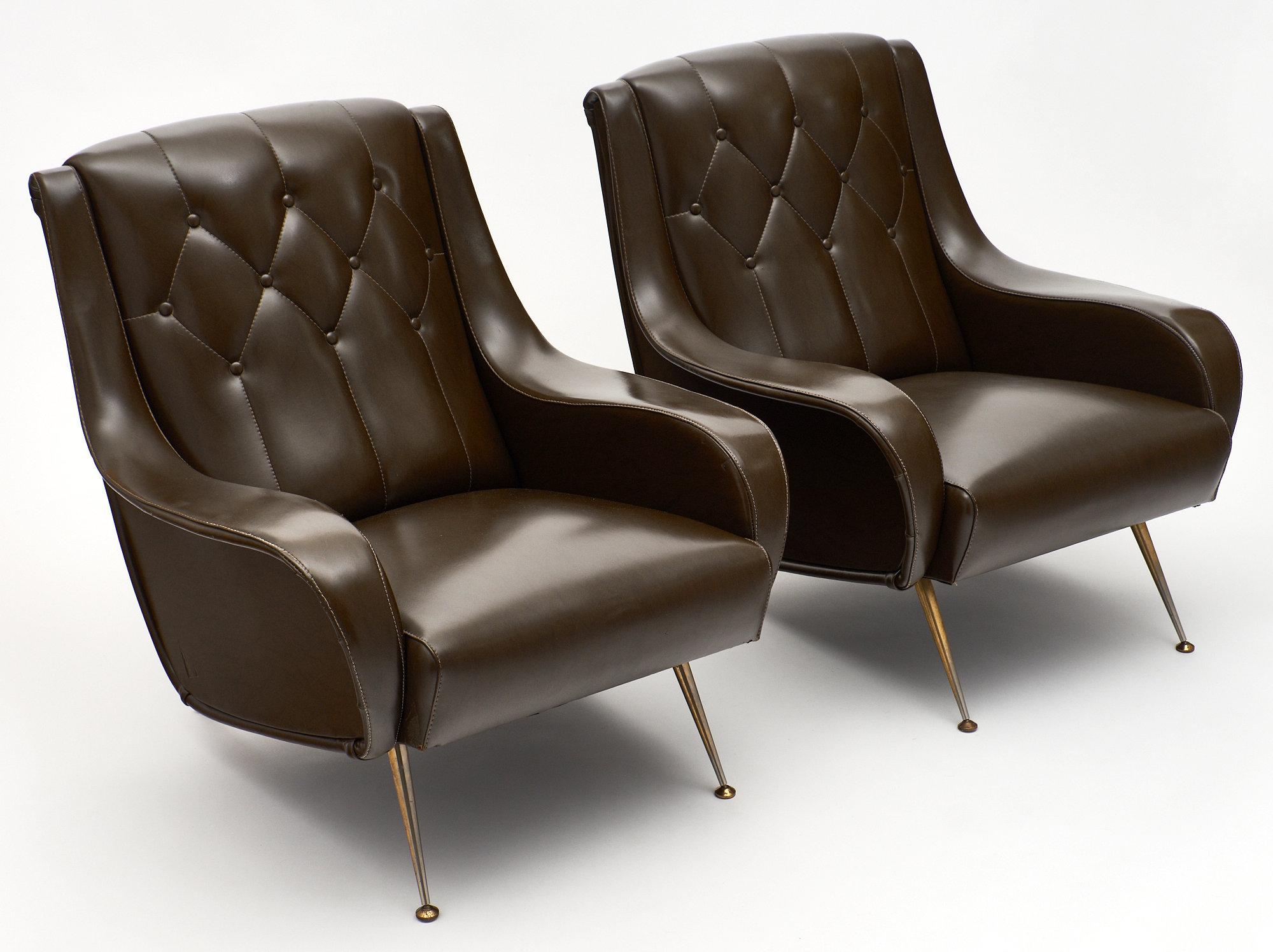Modernist French vintage armchairs. A pair of comfortable armchairs with their original vinyl upholstery, tufted and in very good condition. We loved the dynamic lines and the original solid brass feet. This pair is very comfortable!
