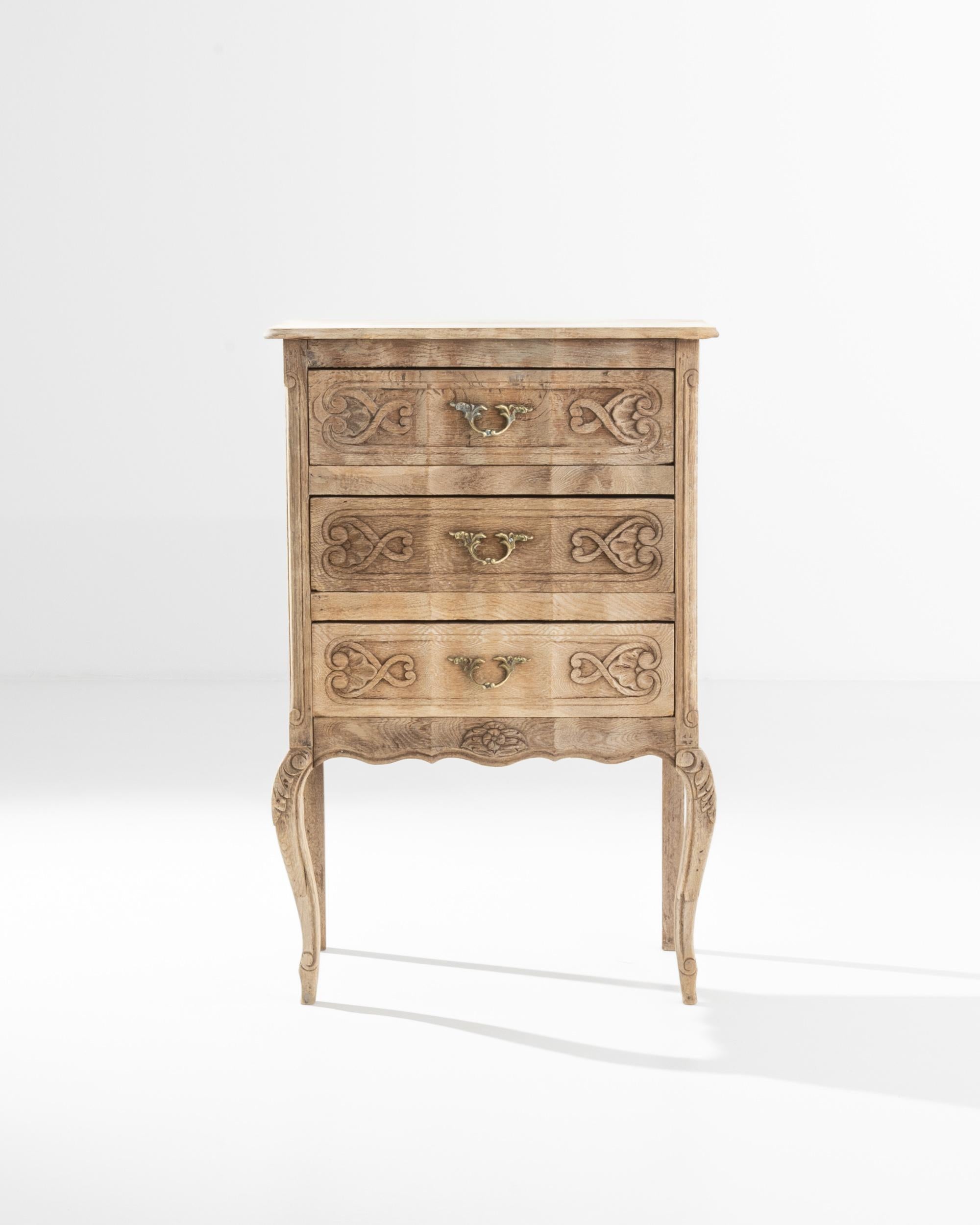 With a convenient small forn, this bleached oak chest of drawers made in France in the 20th century. Three top-down drawers are flanked by animated curved legs, giving a handsome shape to this set of drawers. Scroll and acanthus leaf motifs combine