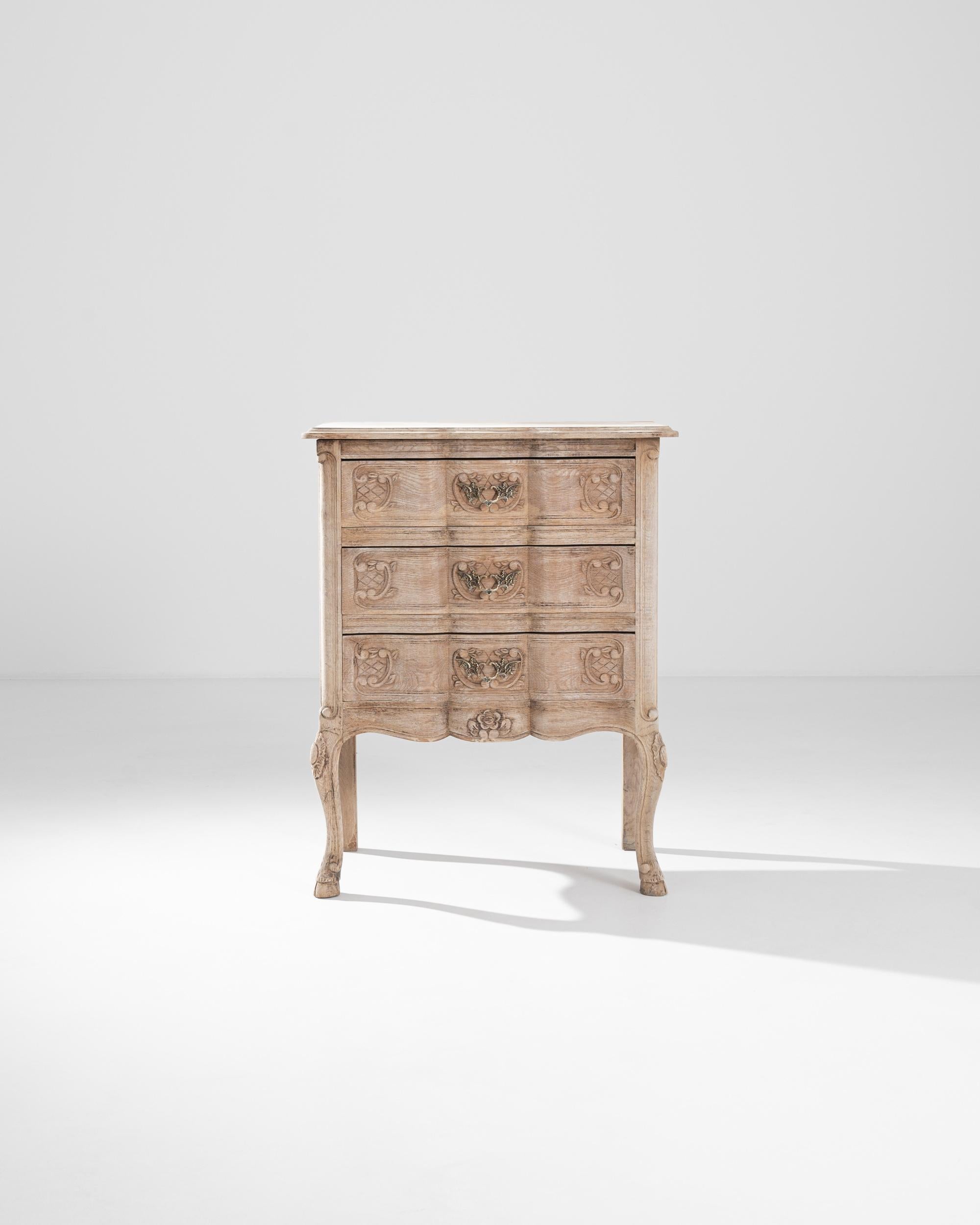 With a convenient small forn, this bleached oak chest of drawers made in France in the 20th century. Three top-down drawers are flanked by animated curved legs, giving a handsome shape to this set of drawers. Scroll and floral motifs combine with