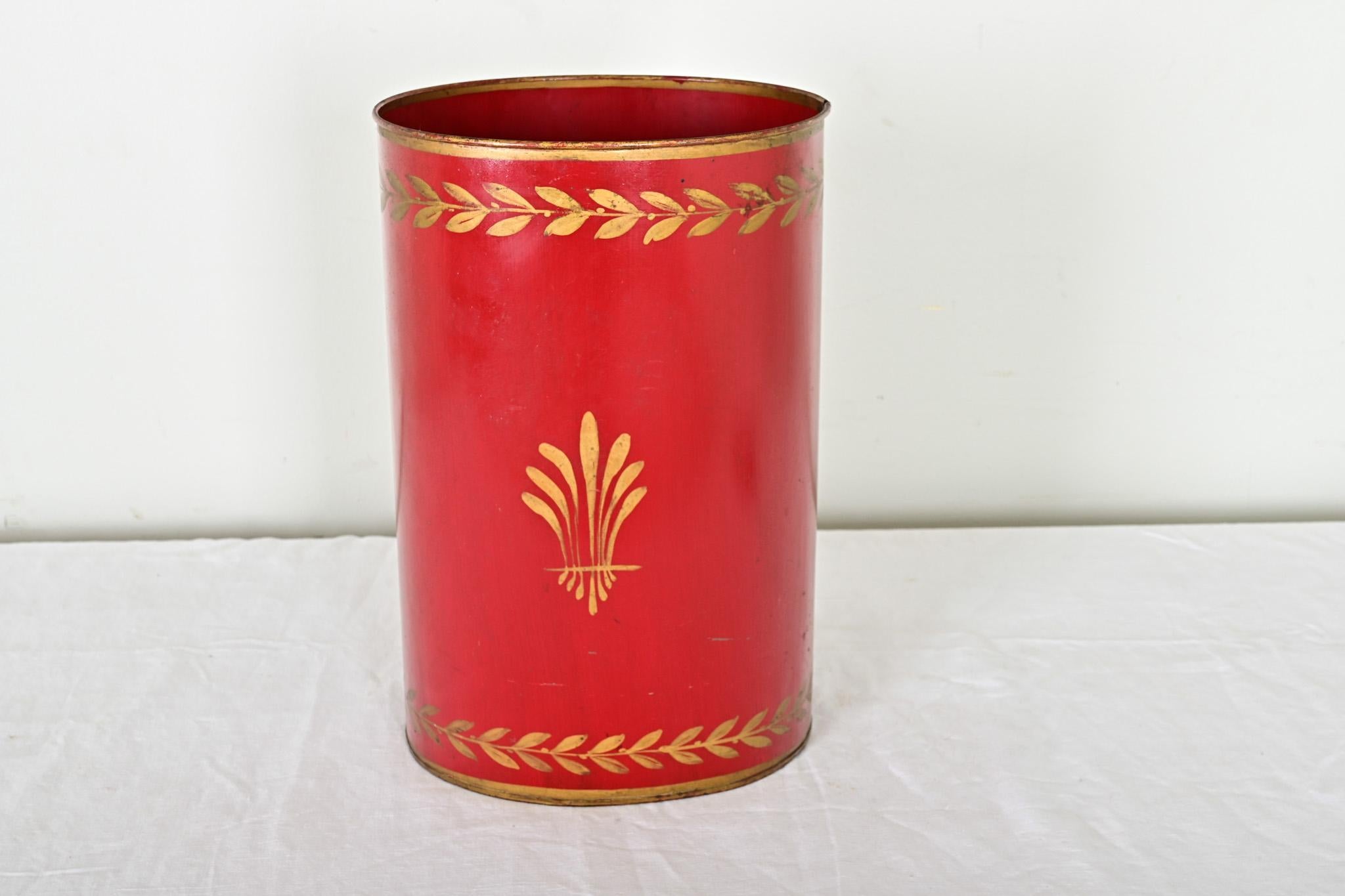 A fiery crimson tole wastebasket from France, 20th century, with gilded, Neoclassical foliate detail over vivid red pigment. The oval shape feels sophisticated for a powder room or office, or as an unexpected vase for dried floral arrangements.