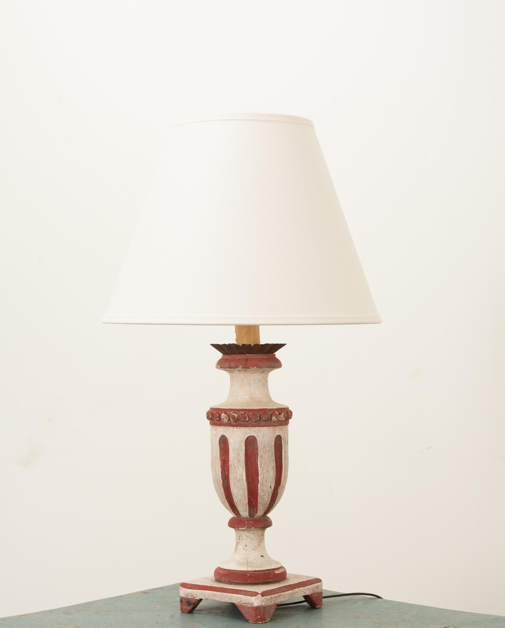 A neat vintage lamp from France with wonderful handcrafted elements. Carved and painted with white and crimson paint and a brass crown accent. Fixed with a new linen shade and recently rewired for the US using UL listed parts. Raised on a square