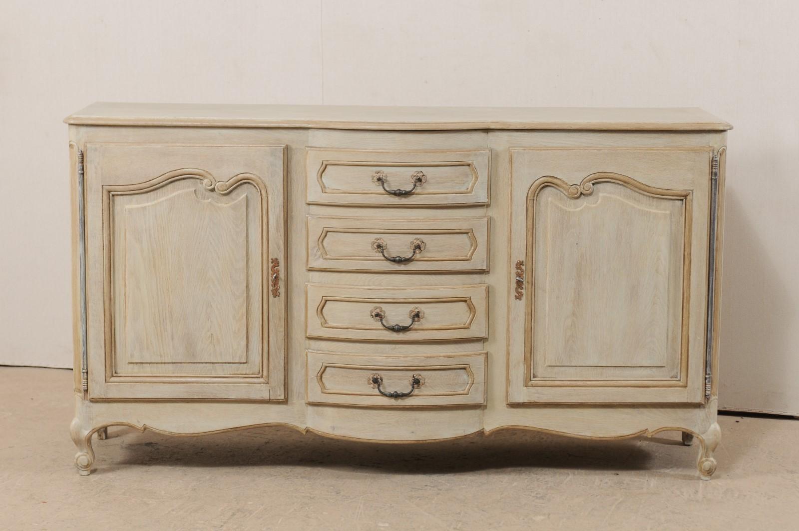 A French painted console cabinet with drawers from the mid-20th century. This vintage 6.25 foot long cabinet from France features a four drawers, set vertically, between a pair of single paneled doors, with a gently scalloped skirt, and raised upon
