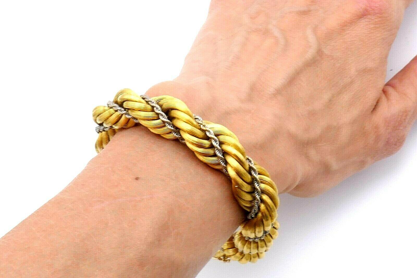 Woven rope chain bracelet made of 18k yellow and white gold. Textured; circa 1970s. Stamped with a hallmark for 18k gold and a maker's mark. Measurements: 8.5