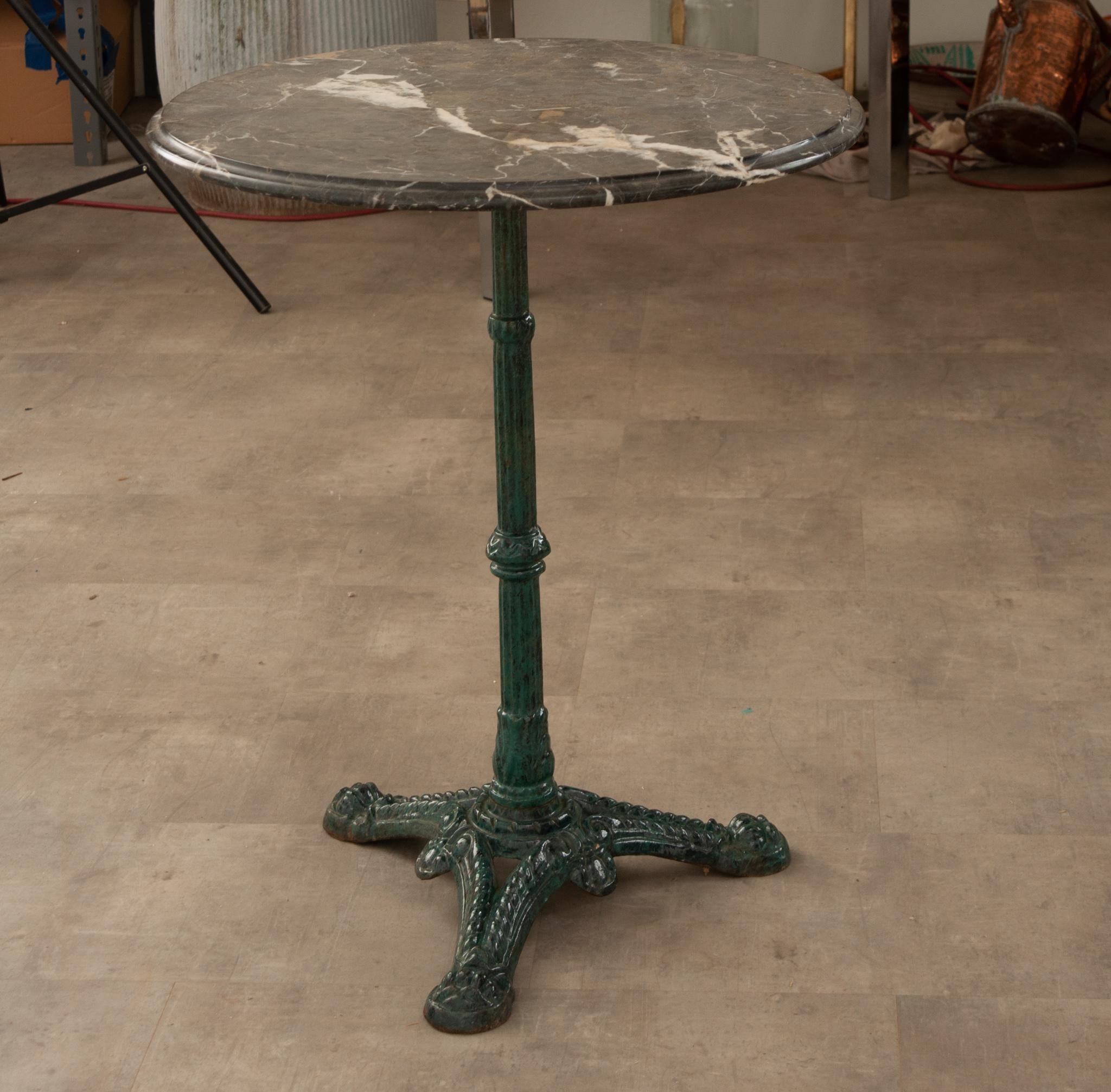A classically composed bistro table from France, circa 1920. The charcoal marble top has interesting white veining and a molded edge that gives it a great finished look. The enameled iron base has a green tint that nicely compliments the top. A
