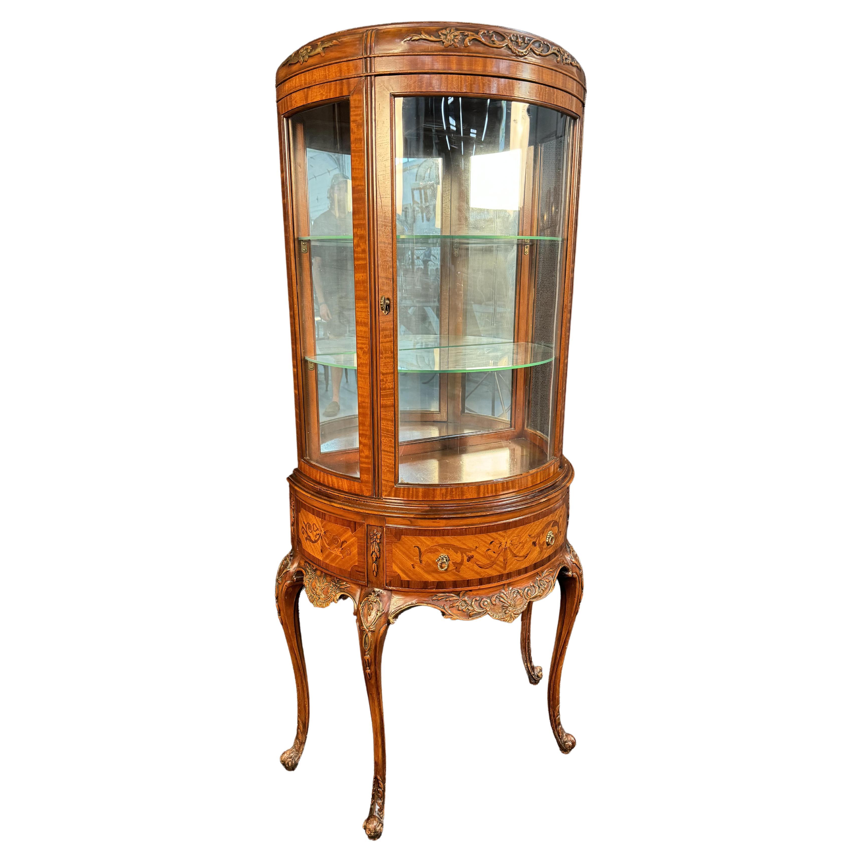 An elegant curved glass china or curio display cabinet or vitrine has satinwood, mahogany and rosewood inlaid marquetry. Please confirm location with seller (NY or NJ)


