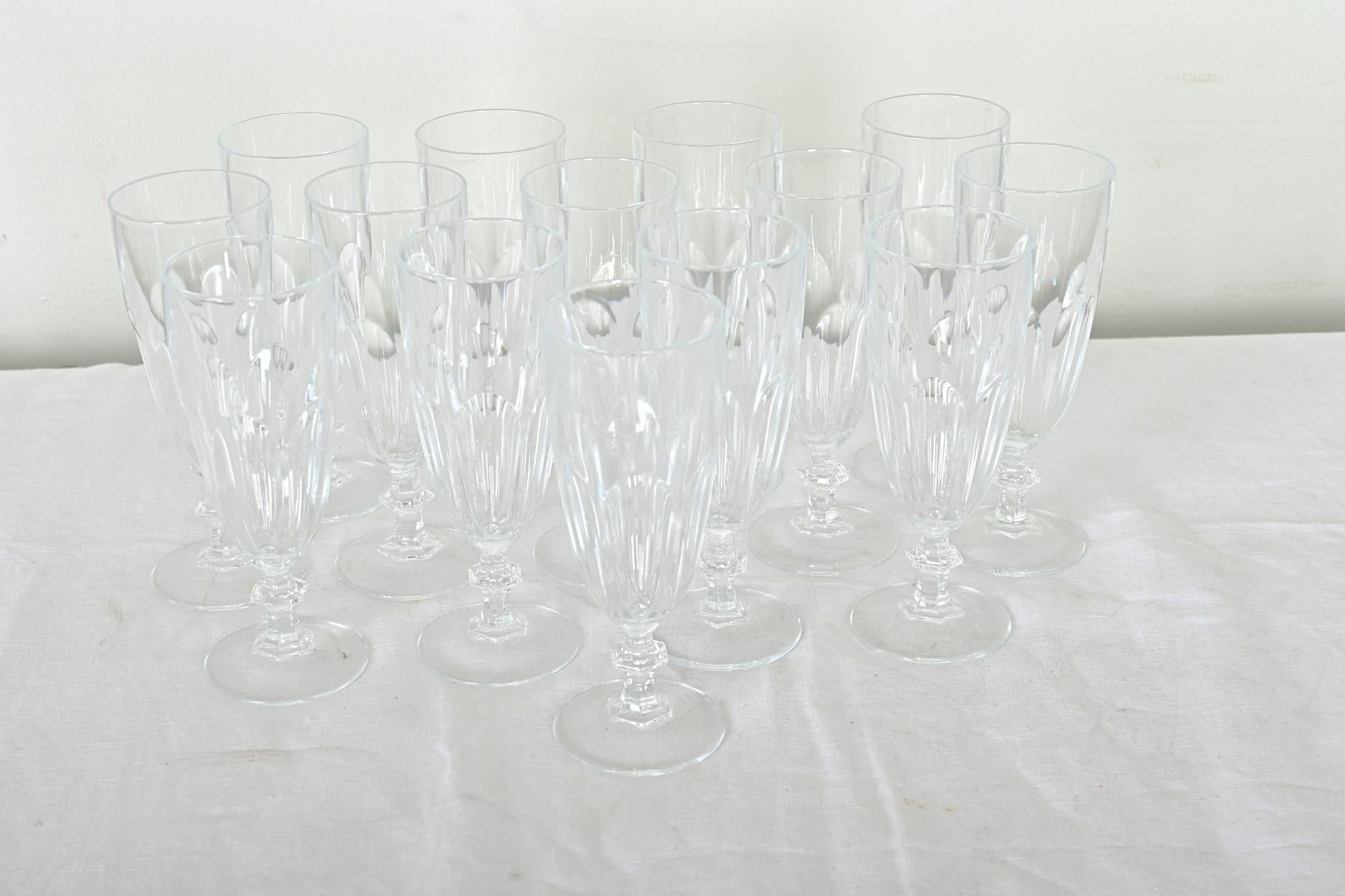 Une magnifique collection de quatorze petites flûtes à champagne en verre taillé, françaises du 20e siècle. Les verres à pied taillés et polis à la main présentent une clarté et une forme magnifiques qui rehaussent n'importe quelle boisson. Ajoutez