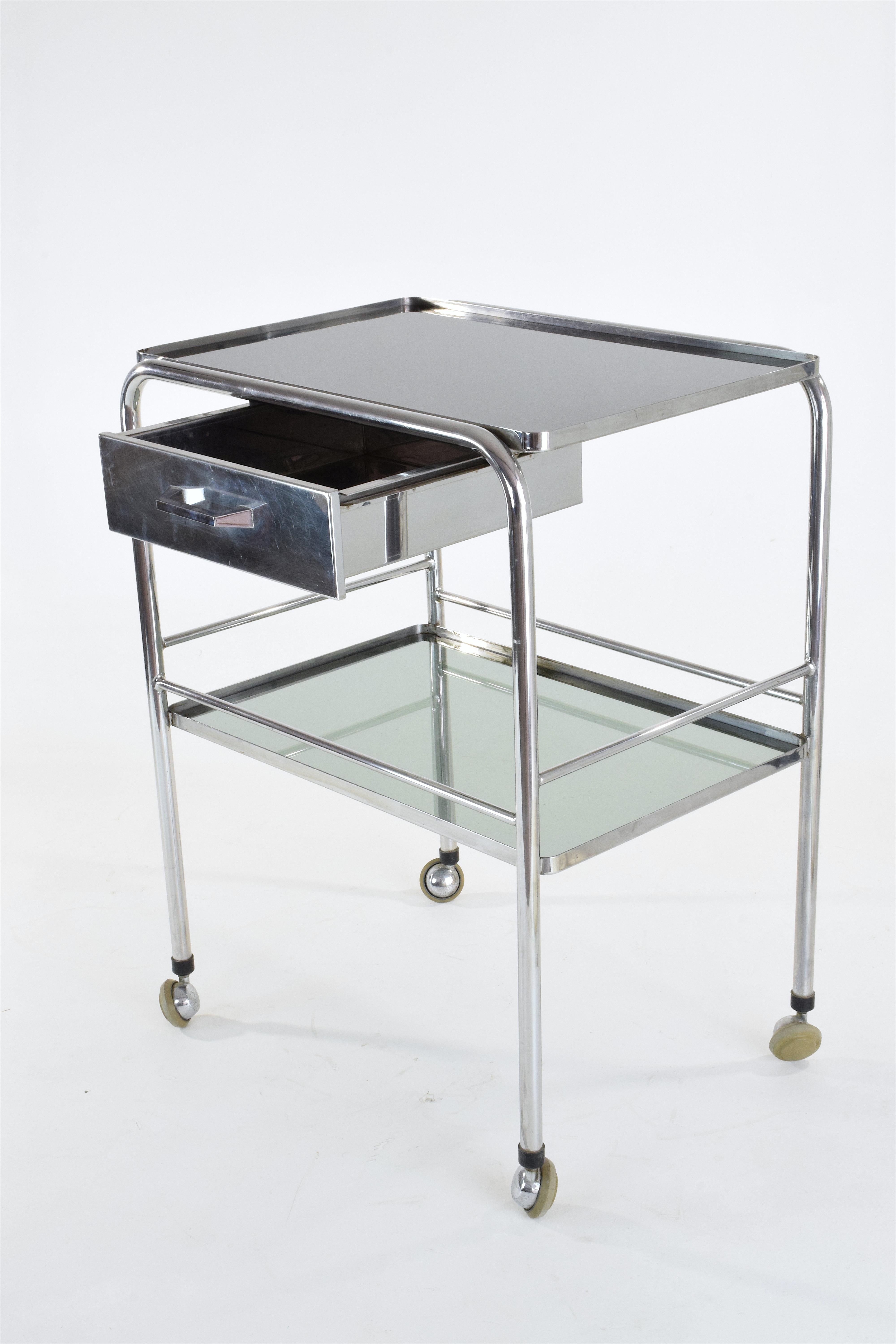 A 20th Century French medical cart in stainless steel with two glass shelves, one drawer and rollers. 
Could be used as an original bar cart since it is practical to move around or as a great storage space, bathroom vanity or cabinet.
 
-----

We