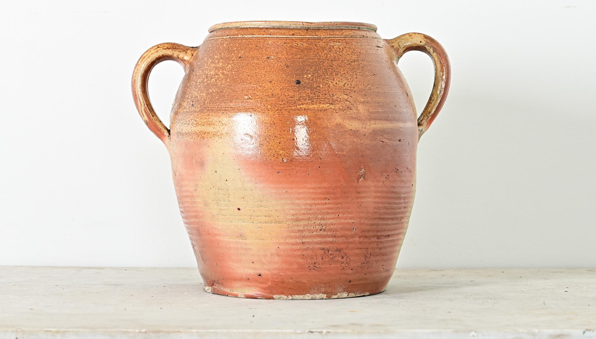 A French vintage glazed stoneware confit-type pot with two handles for balancing the weight. This utilitarian Provincial vessel would have been used to store and preserve foods (like a confit or rillette) as there is a small hole pierced in the wall