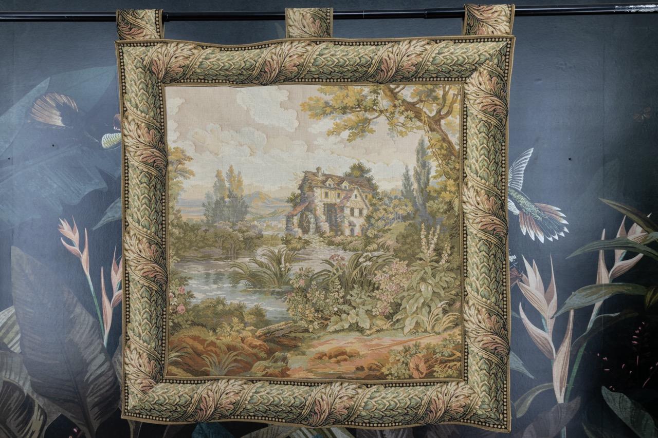 Arazzo vintage francese, appeso alla parete, della seconda metà del XX secolo.
Un bellissimo arazzo francese in stile Aubusson, con un bordo di foglie che presenta un paesaggio, una casa con una ruota ad acqua e un giardino - colori tenui e un bel