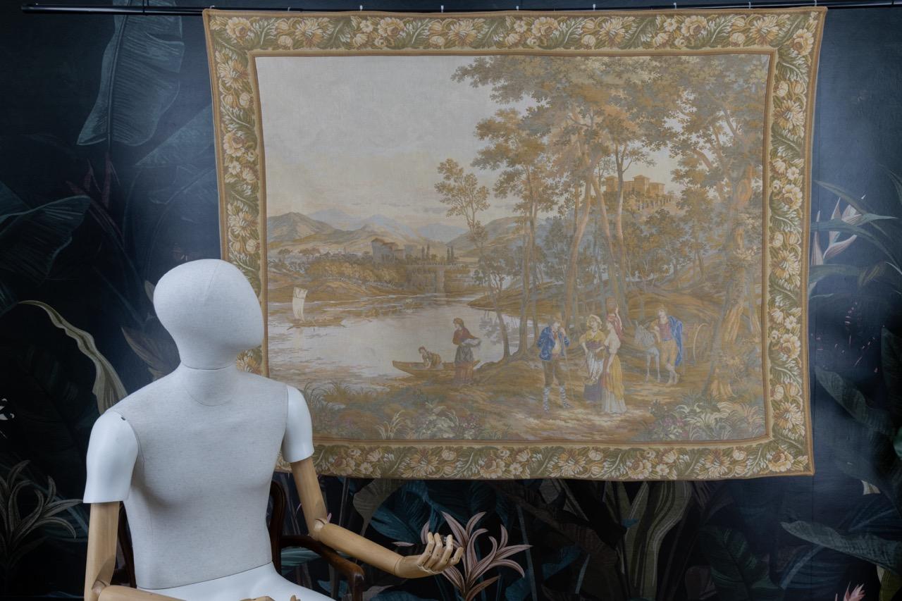 French Vintage Tapestry from the mid-20th century.
A beautiful French tapestry in Aubusson style, within a flower border featuring a landscape - mountains, castles, and a river or lake with boats - soft colors and a nice motif.
Dimensions: 164 cm /