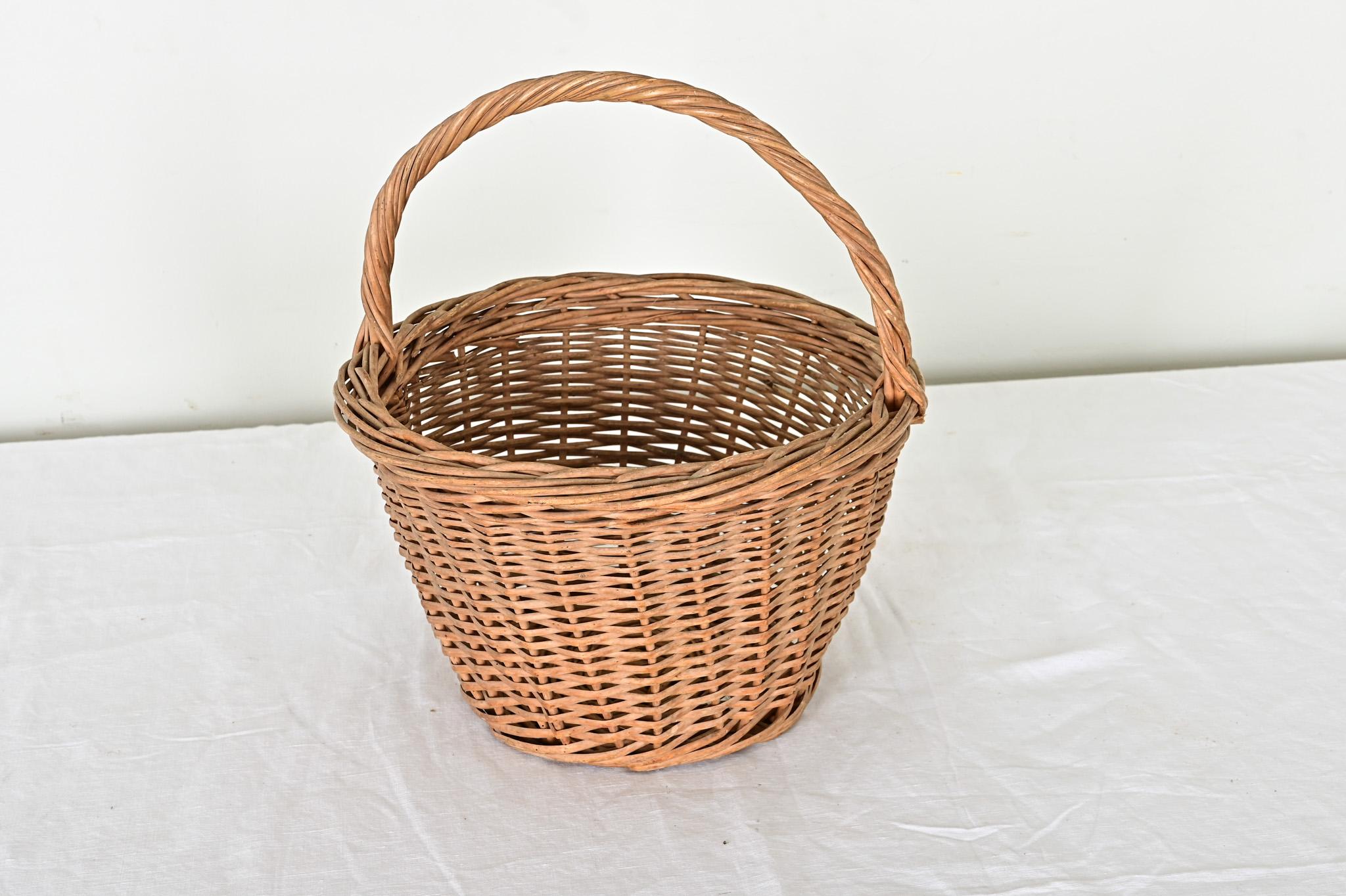 Un delizioso cesto di vimini francese vintage della metà del XX secolo. Questo robusto cesto è stato realizzato per resistere alla prova del tempo. Originariamente utilizzato per raccogliere frutta, verdura e altri prodotti dell'orto, è un