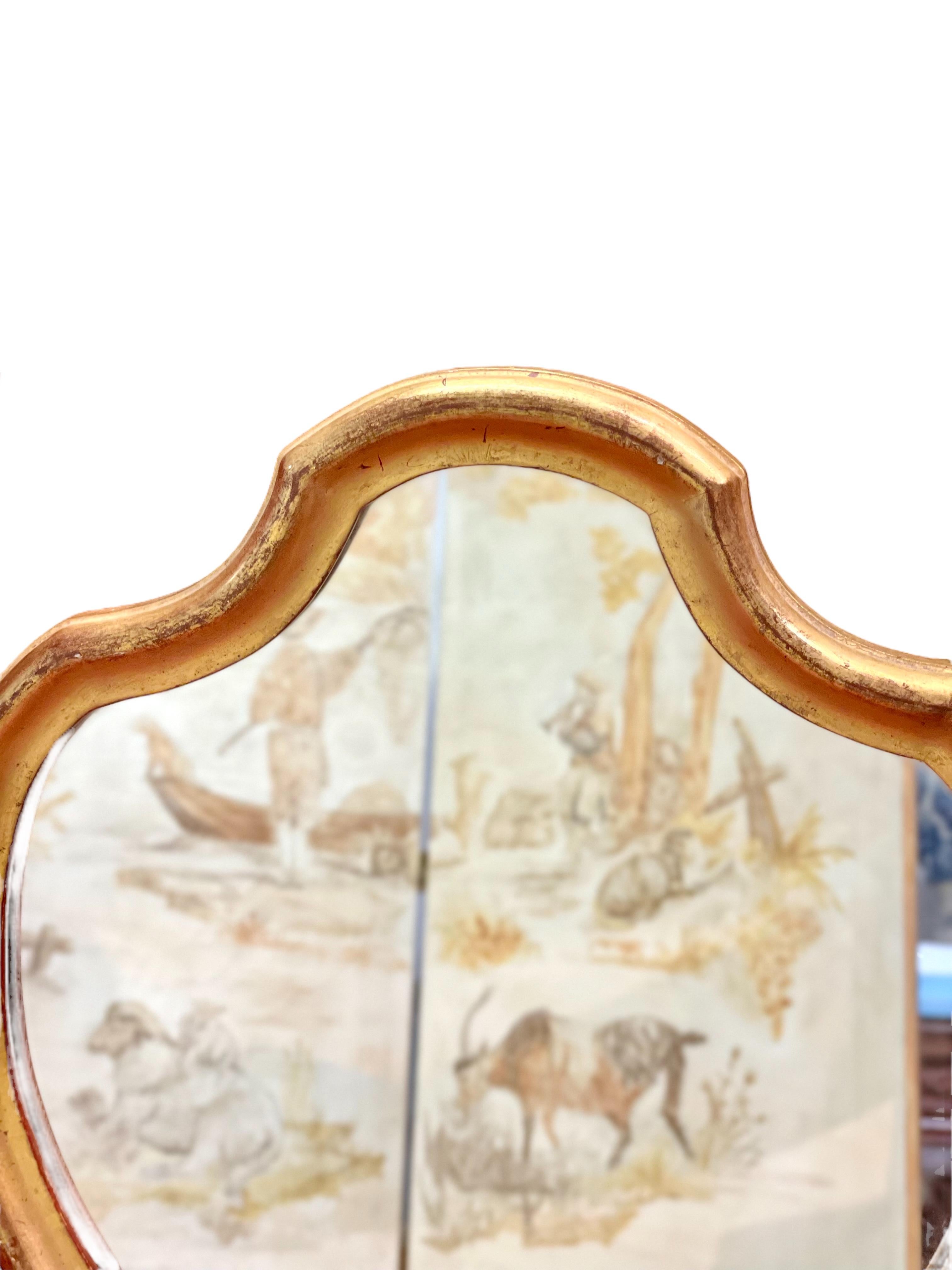 A very decorative violin-shaped giltwood mirror, dating from the end of the 19th century. This elegant wall mirror has a lovely worn patina, with the original red gesso color. It would be ideal in a hallway, or smaller room, its gleaming golden