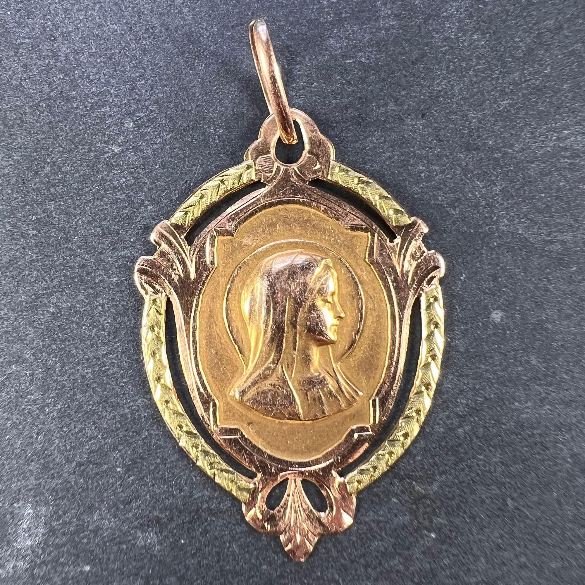 A French 18 karat (18K) rose gold charm pendant designed as a shield-shaped medal depicting the Virgin Mary in profile within a yellow gold wreath frame. Engraved to the reverse with the monogram SS and dated 27 Mai 1923. Stamped with the eagle's