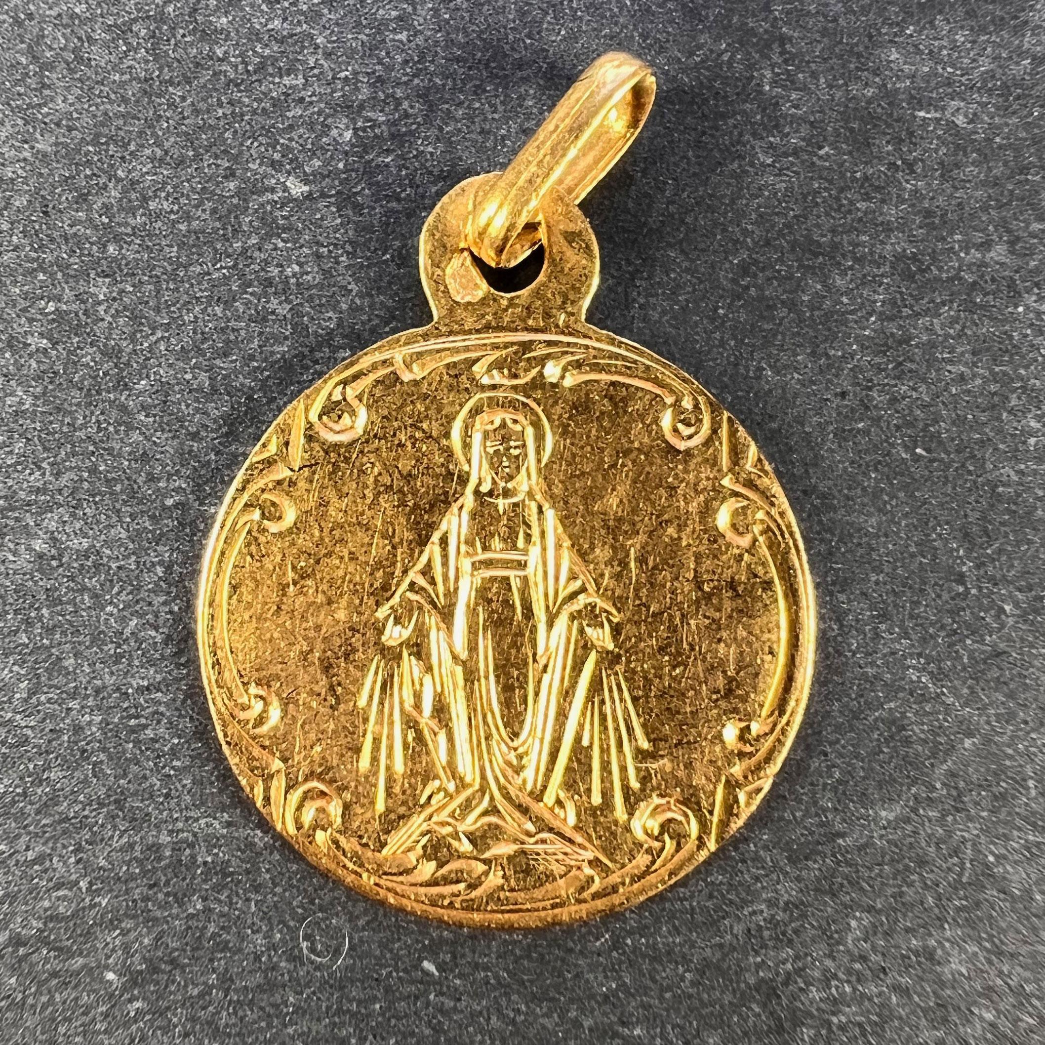 A French 18 karat (18K) yellow gold charm pendant designed as a round medal engraved with the Virgin Mary. Engraved to the reverse with the monogram BG and dated '29 Mars 1900'. Stamped with the eagle's head for 18 karat gold and French manufacture,