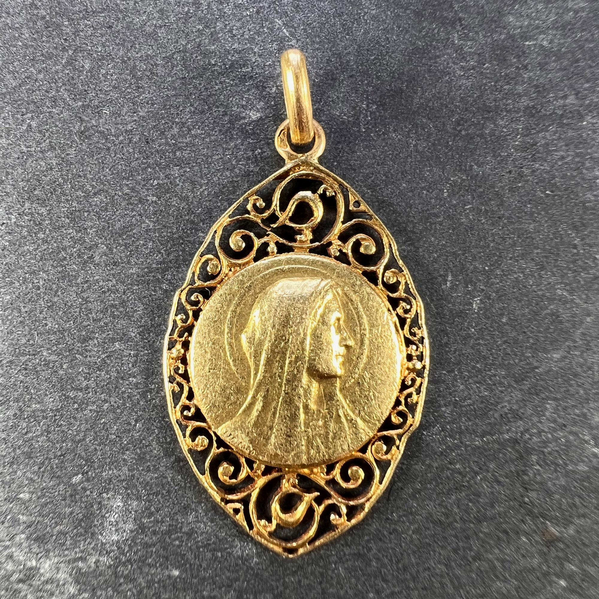 A French 18 karat (18K) yellow gold charm pendant designed as a round medal depicting the Virgin Mary within a navette shaped frame with pierced curliques, engraved with a monogram for JD to the reverse. Signed L. Tricard and P.L.Dasset. Unmarked