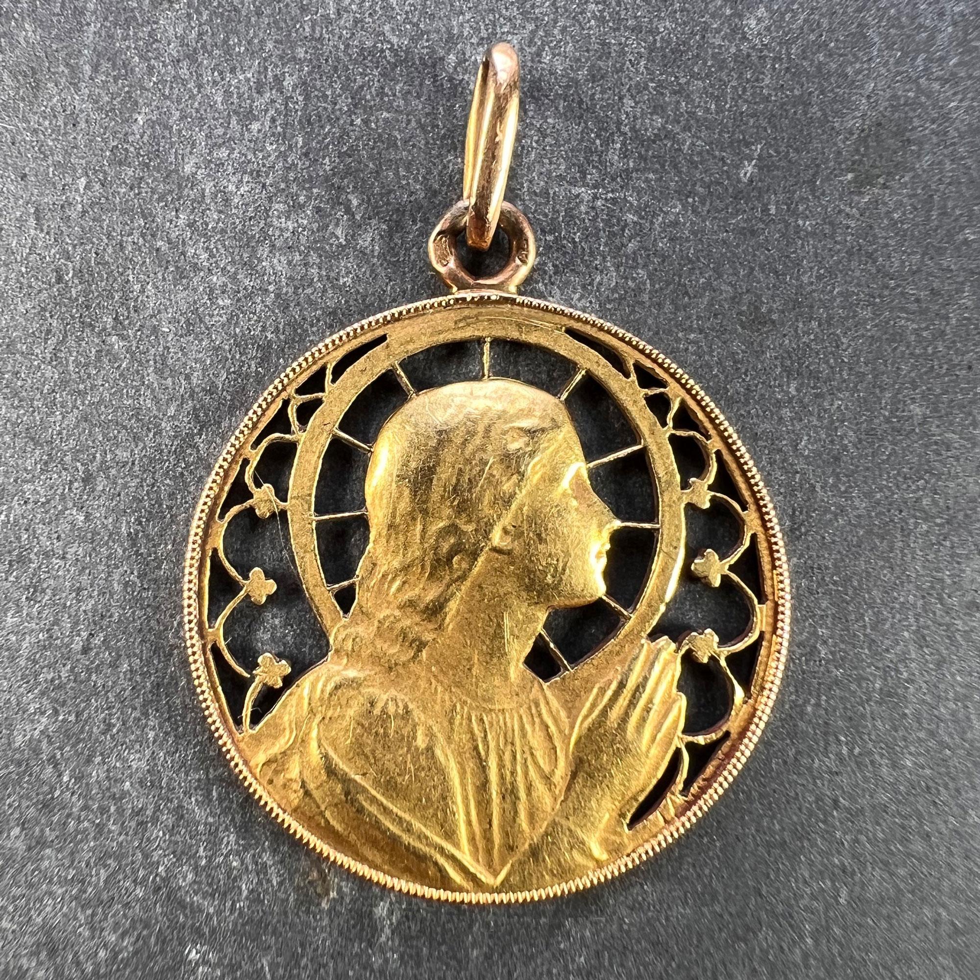 Pendentif à breloques français en or jaune 18 carats (18K) conçu comme une médaille ronde représentant la Vierge Marie dans un cadre ajouré conçu pour ressembler à une auréole et à un vitrail. Le revers est gravé AMR avec la date 
