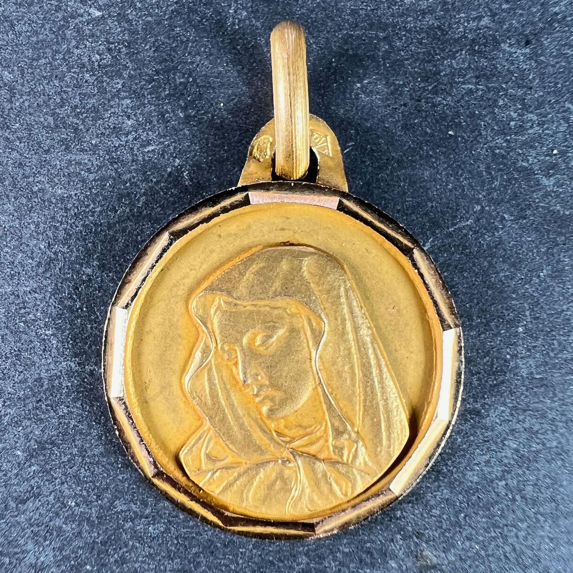 An 18 karat (18K) yellow gold charm pendant designed as a round medal with faceted frame depicting the Virgin Mary. Stamped with the eagle’s head for French manufacture and 18 karat gold, and an unknown maker’s mark.

Dimensions: 2 x 1.7 x 0.1 cm