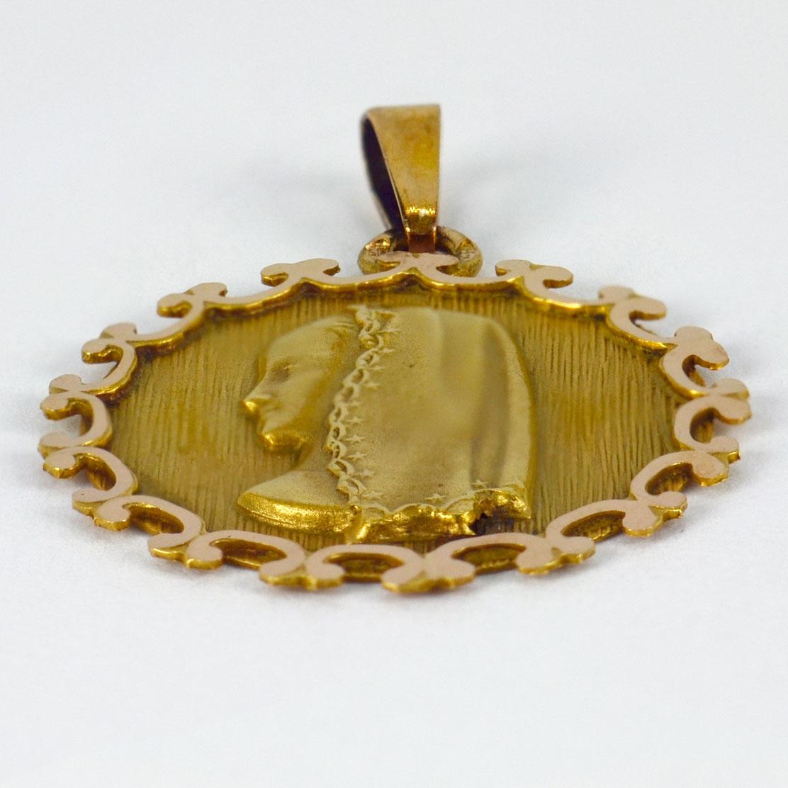 An 18 karat (18K) yellow gold pendant designed as a round medal with petal edges depicting the Virgin Mary. Stamped with the eagle’s head for French manufacture and 18 karat gold, with unknown maker’s mark.

Dimensions: 2.4 x 2.1 x 0.1 cm (not