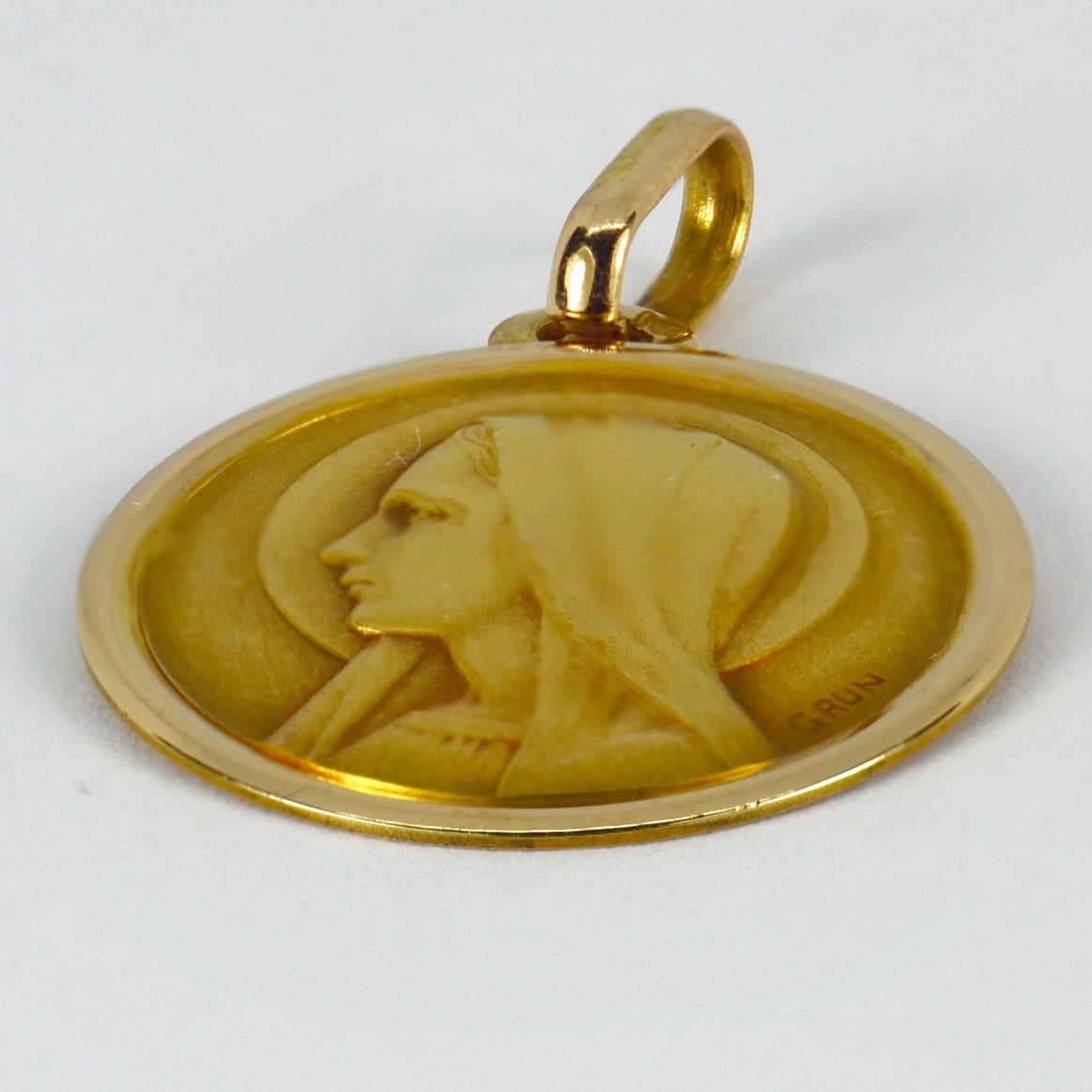 An 18 karat (18K) yellow gold pendant designed as a round medal depicting the Virgin Mary. Signed GRUN. Stamped with the eagle’s head for French manufacture and 18 karat gold, with maker’s mark for Perroud.

Dimensions: 2.2 x 1.9 x 0.1 cm (not