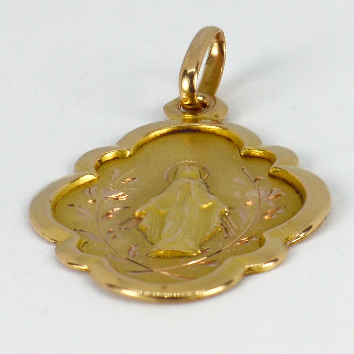 An 18 karat (18K) yellow gold pendant designed as a medal depicting the Virgin Mary with a scalloped surround. Engraved to the reverse ‘Souvenir de ma premiere Communion (abbreviated), Montmorency de 7 Juin 1923’ with the monogram DG. Stamped with
