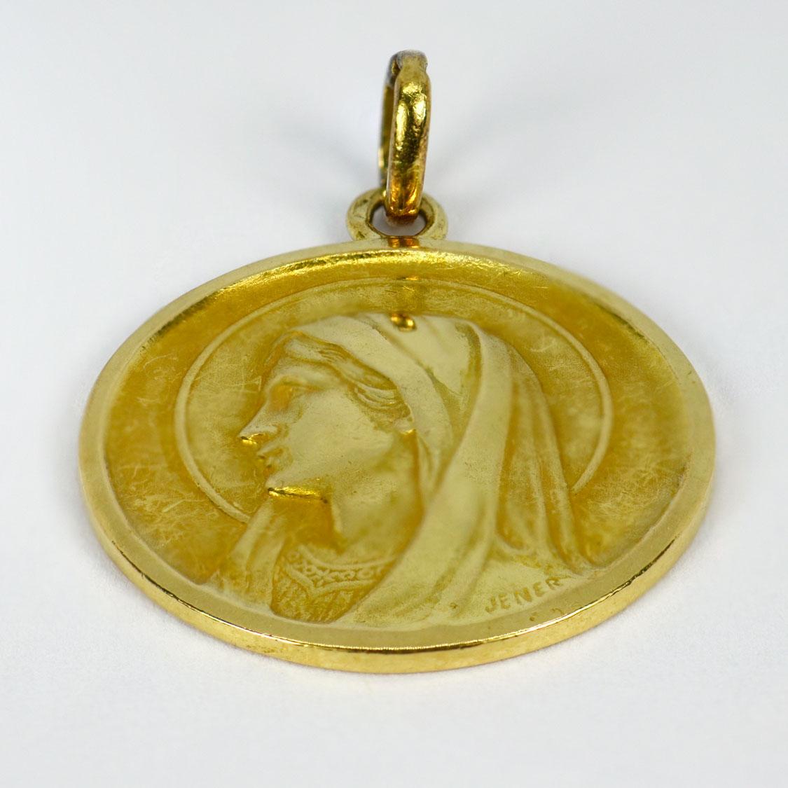 Pendentif en or jaune 18 carats (18K) conçu comme une médaille représentant la Vierge Marie. Signé Jener. Estampillé de la tête d'aigle de fabrication française et de l'or 18 carats.

Dimensions : 2.6 x 2.2  x 0,15 cm (sans anneau de saut)
Poids :